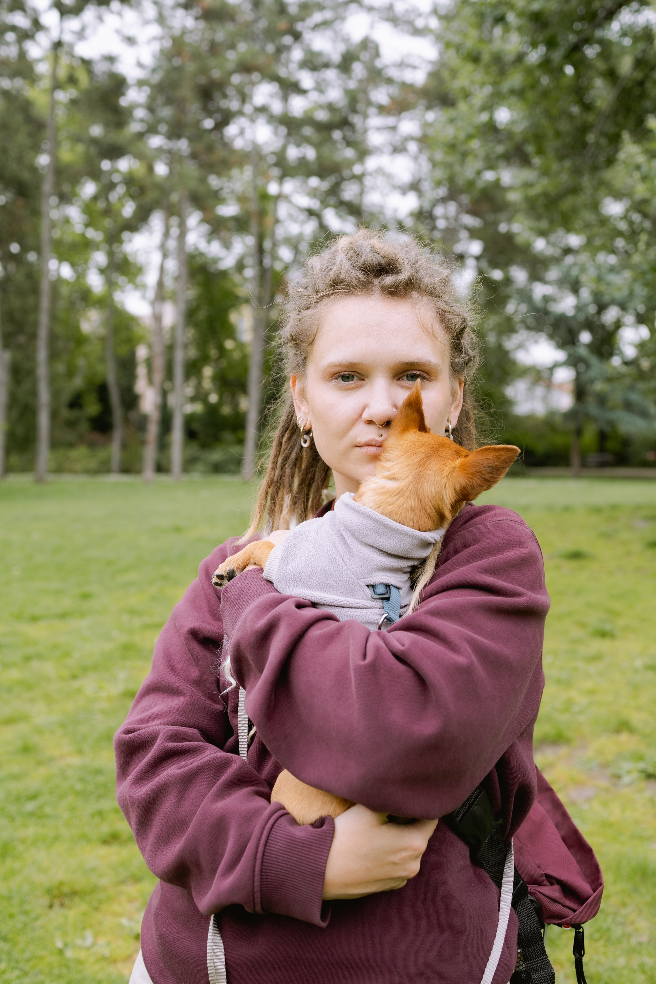 Юля с дредами держит своего той-терьера Роки на руках, глядя в камеру.