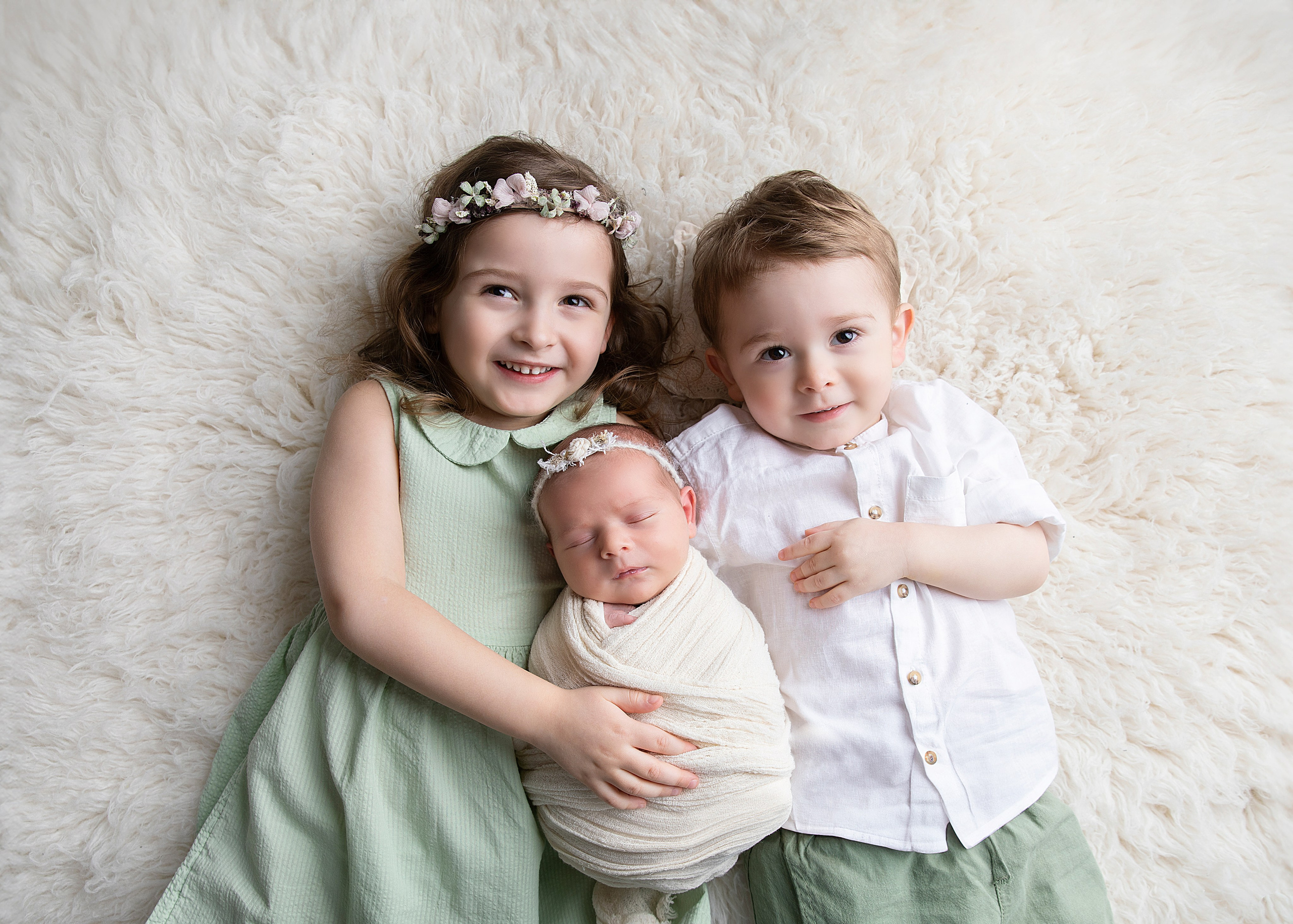 "Ett äldre syskon som sitter försiktigt bredvid sin nyfödda bror eller syster. Denna bild fångar den ömma och beskyddande relationen mellan syskonen och är idealisk för nyfödda fotograferingar."