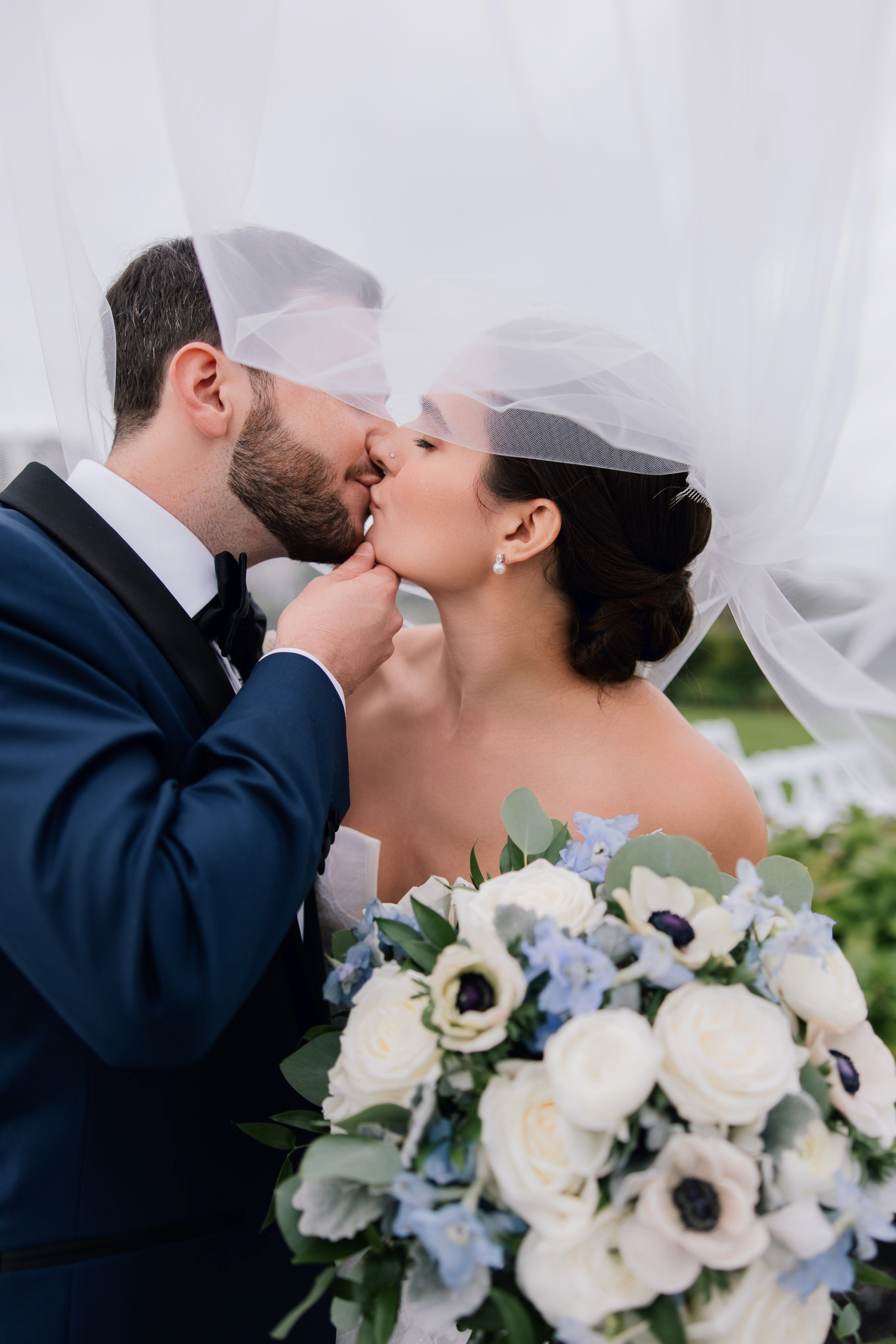 a bride and groom kissing under a veil