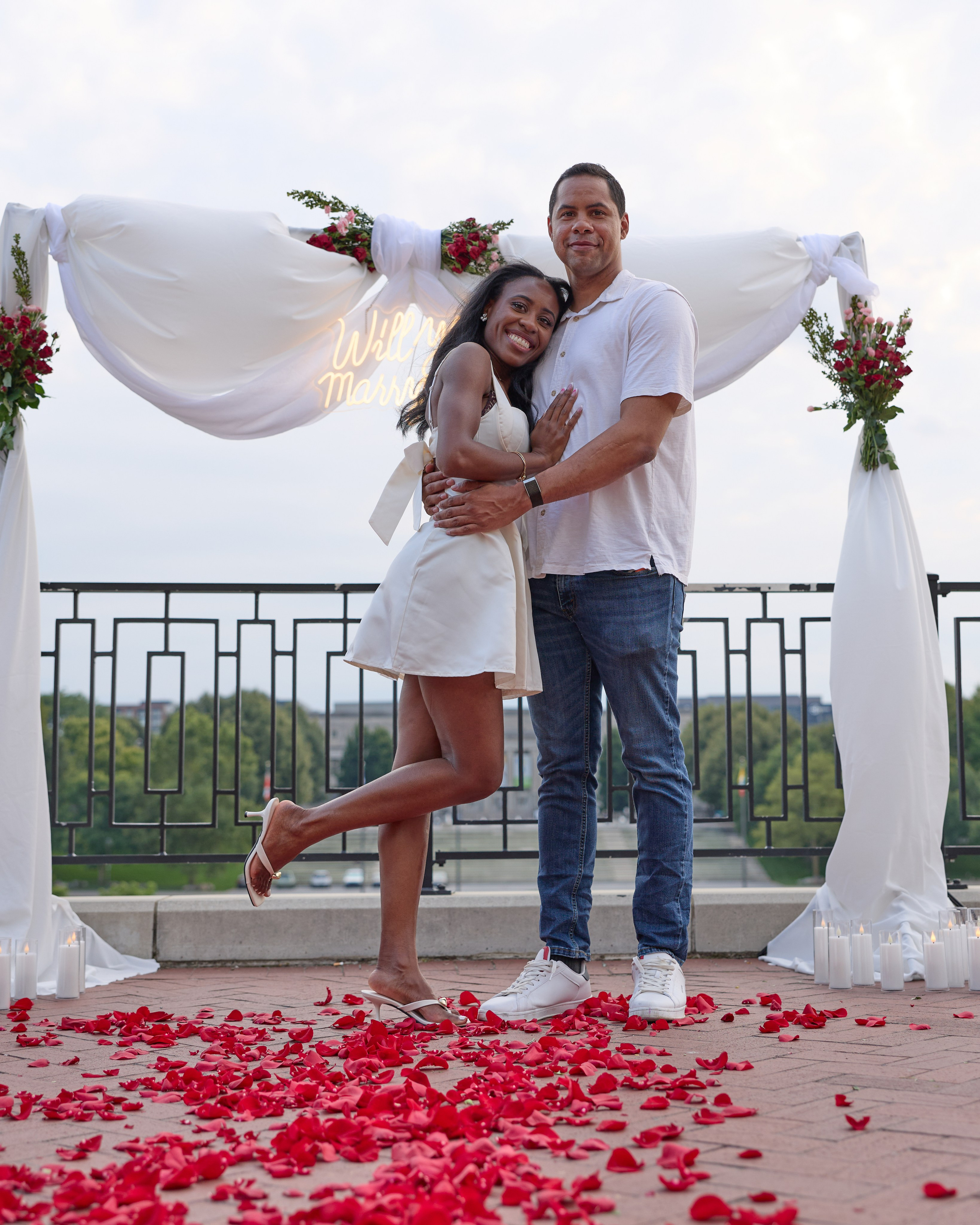 Playful couple posing under a flower arch covered in rose petals in Columbus, Ohio