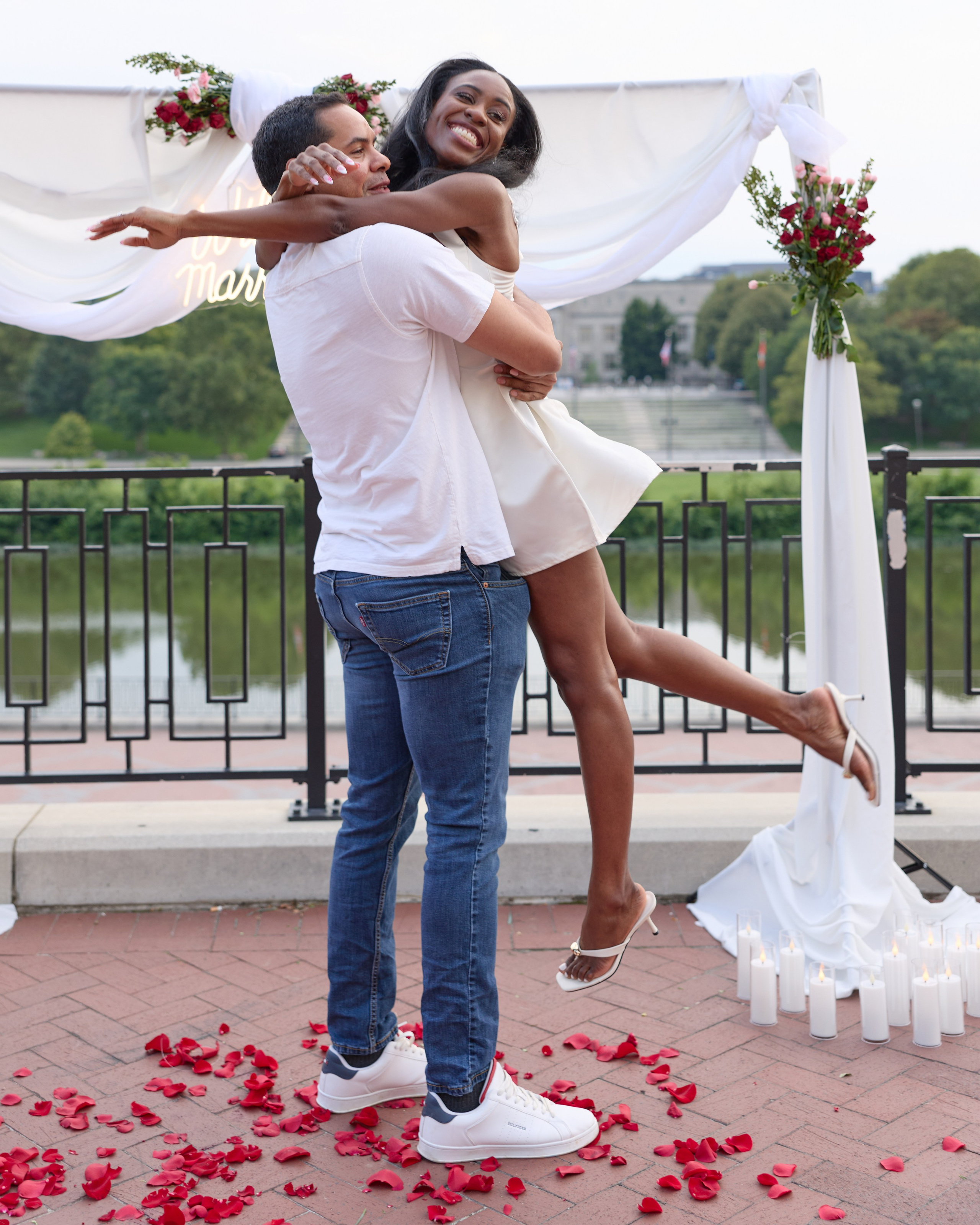 Joyful groom lifting his bride-to-be under the proposal arch in Columbus, Ohio