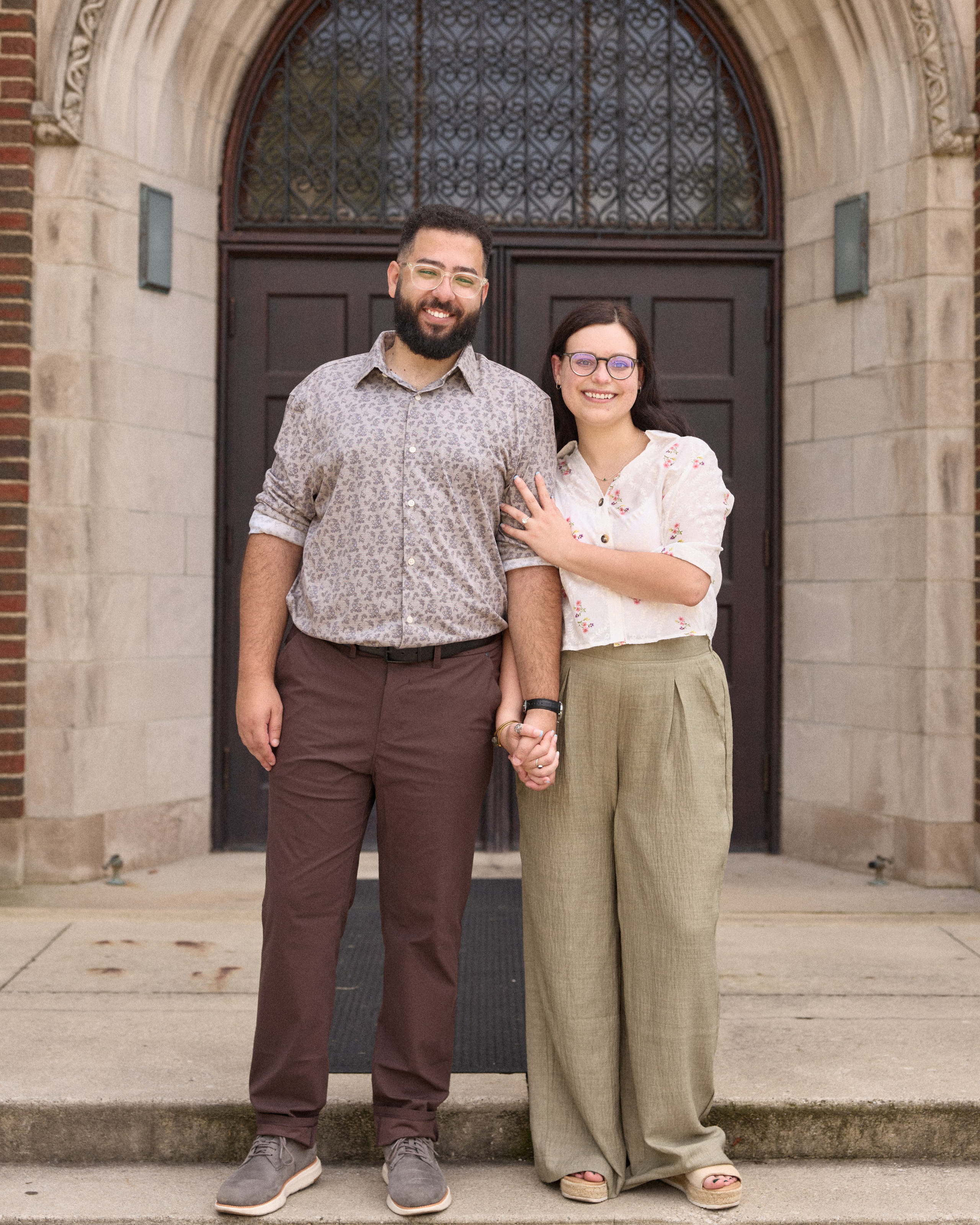 Engaged couple posing before an arched university entrance in Columbus, Ohio