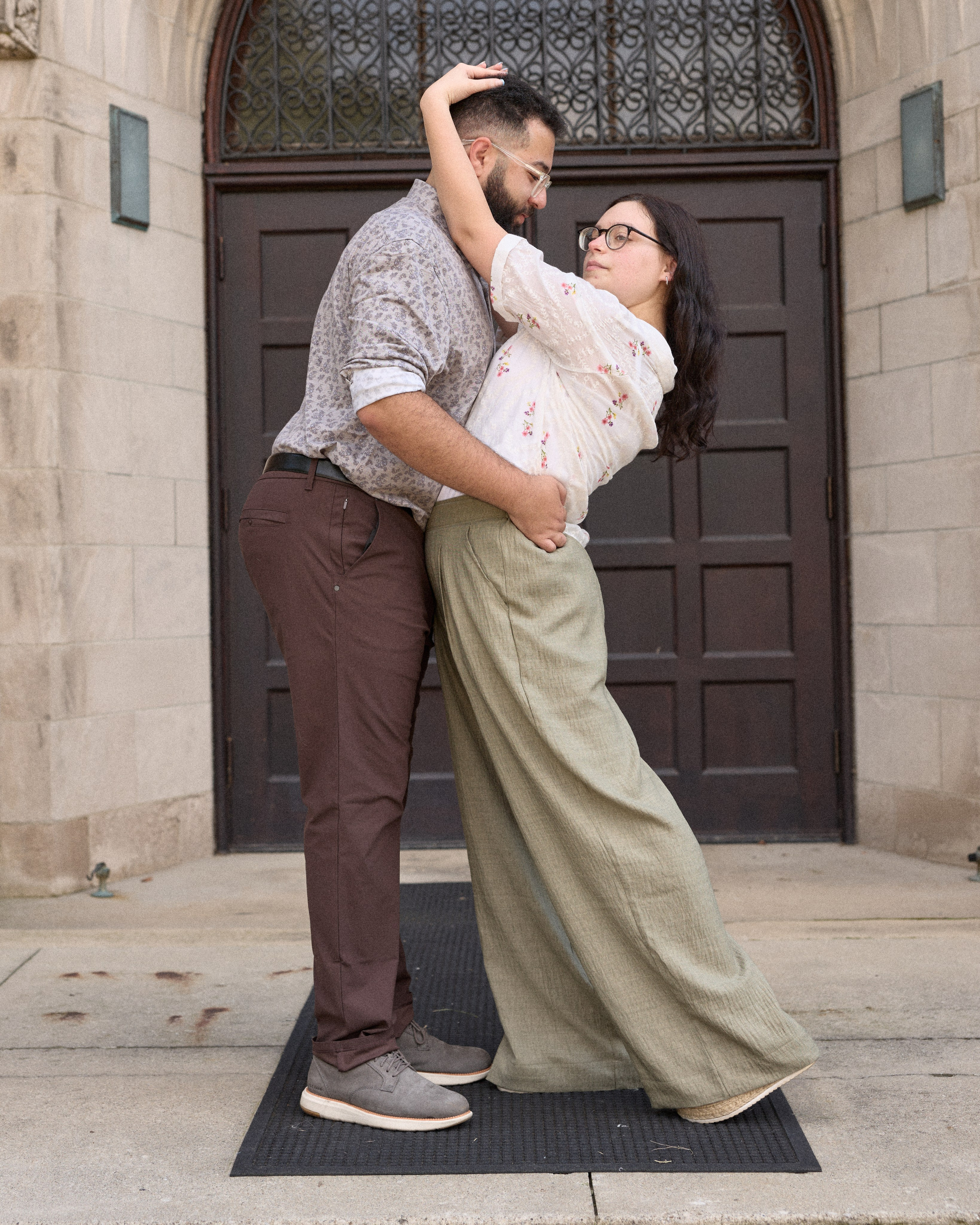 Full-length portrait of an engaged couple in front of campus doors in Columbus, Ohio