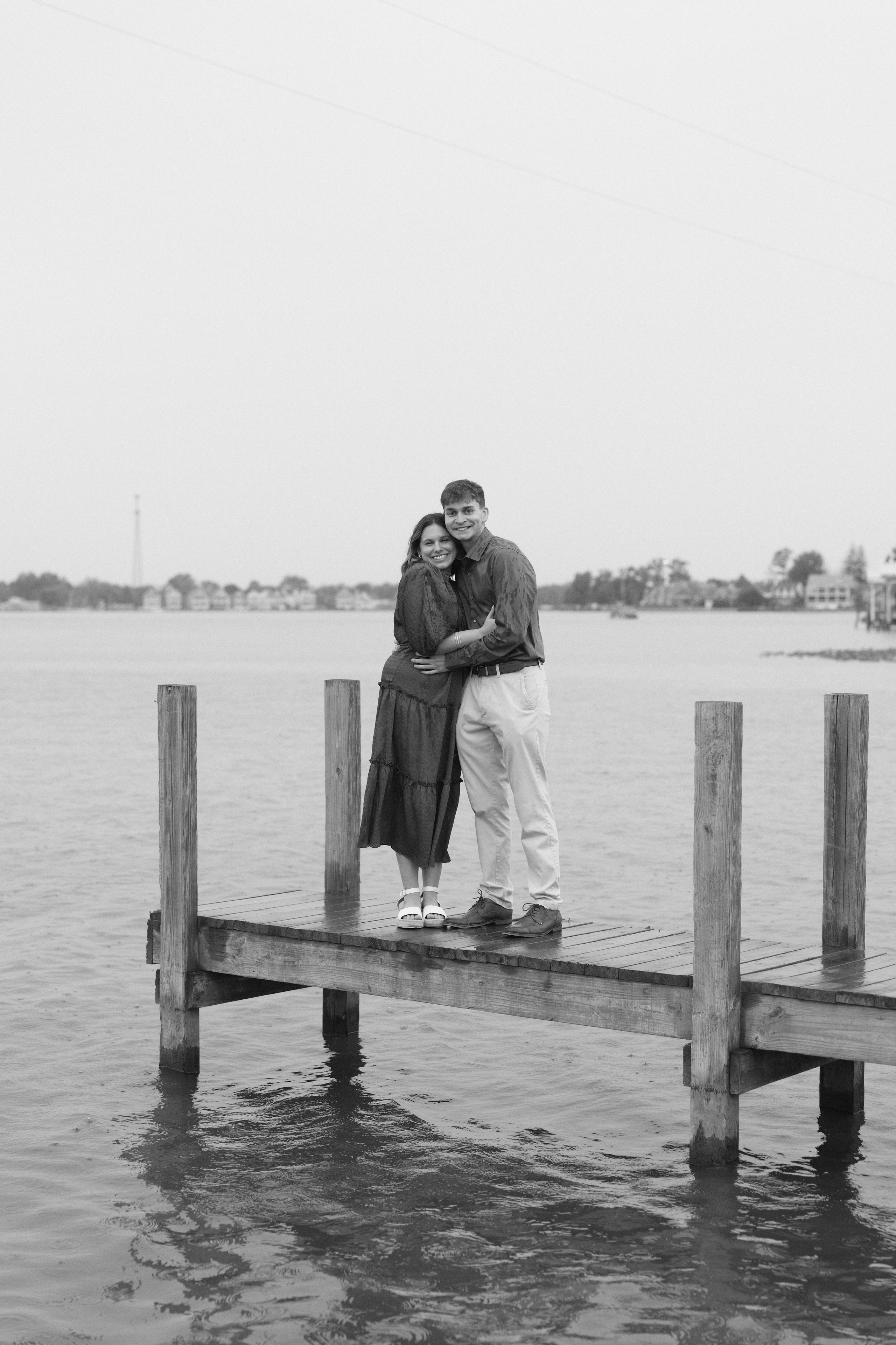 Black and white photo of a couple kissing on a wooden dock over the lake in Ohio