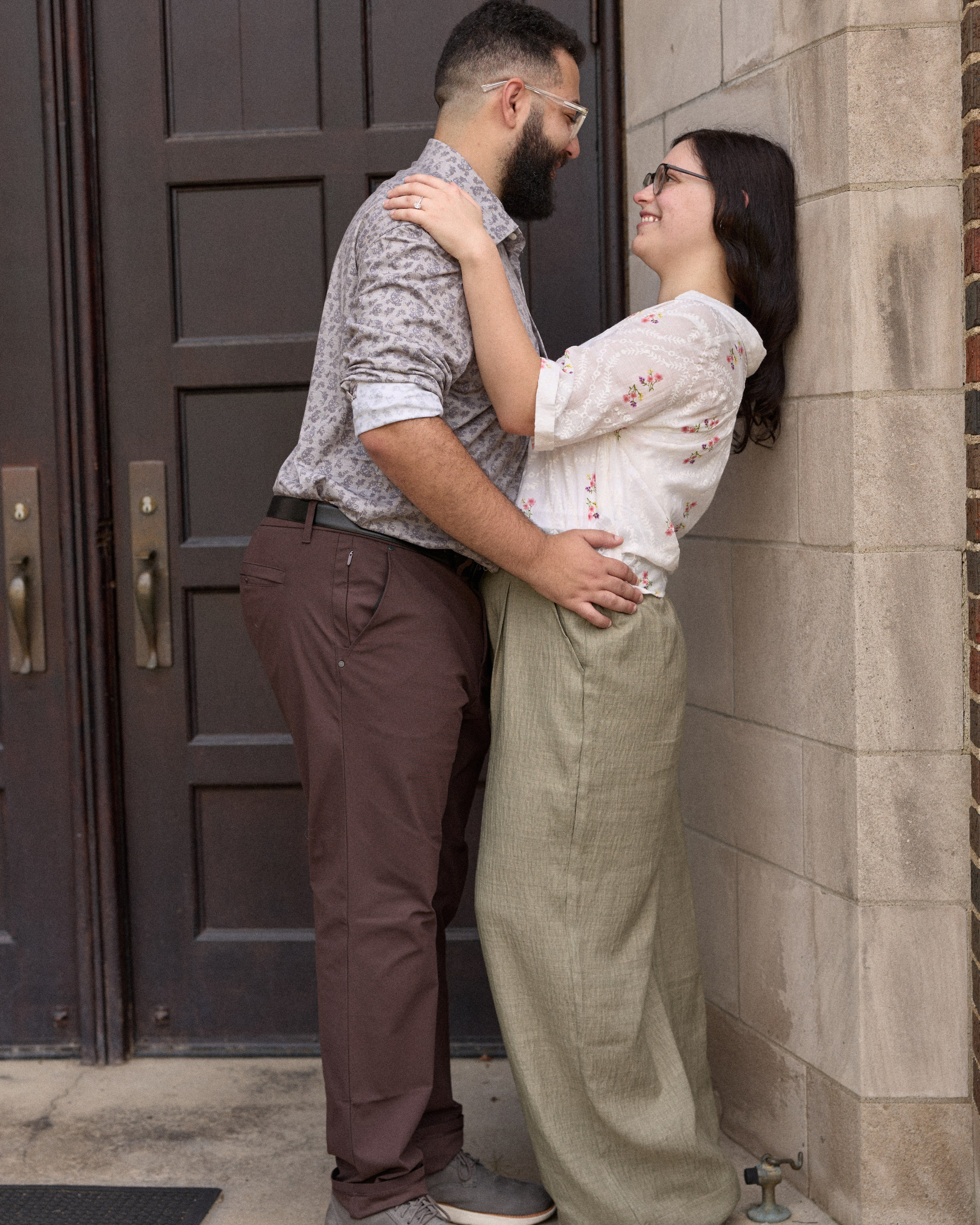 Couple leaning against a stone wall by a campus doorway in Columbus, Ohio