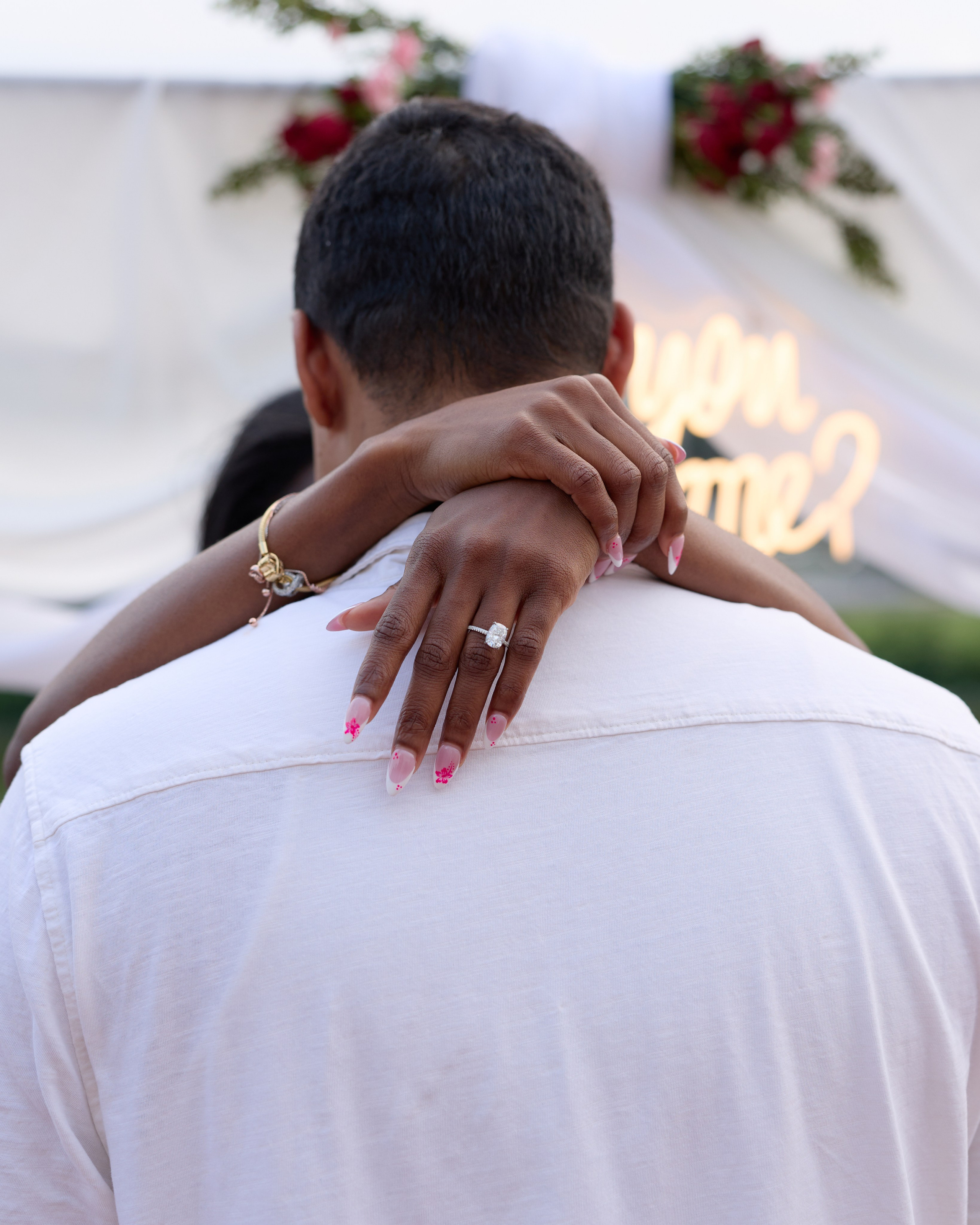 Embrace from behind with her ring hand on his shoulder under the proposal arch in Columbus, Ohio