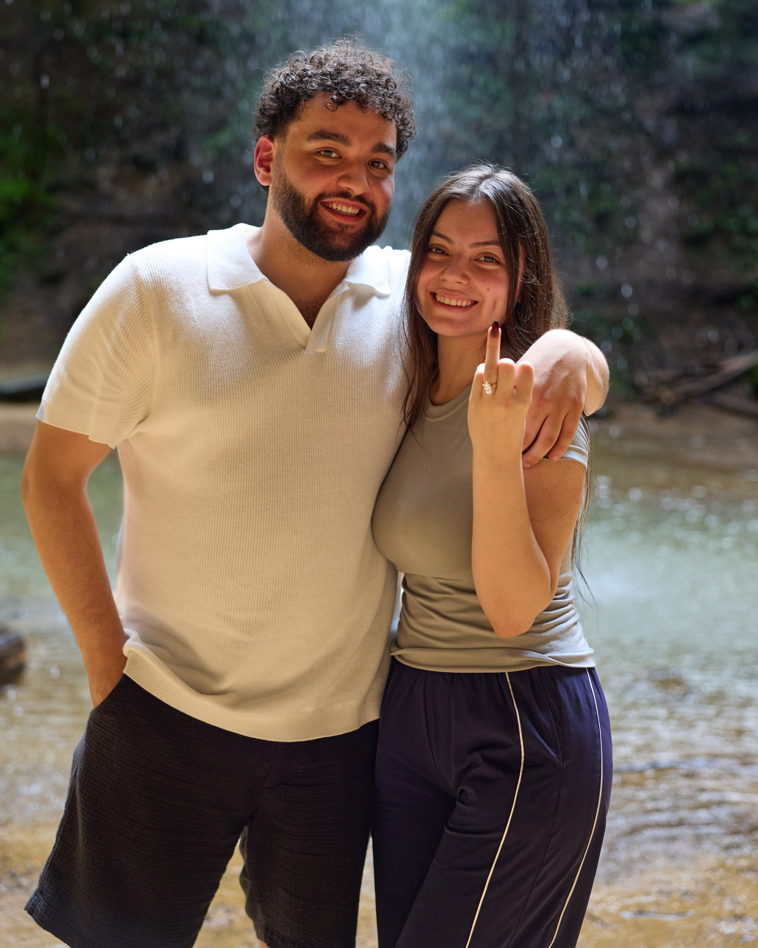 Smiling couple portrait with a waterfall behind them in Hocking Hills, Ohio