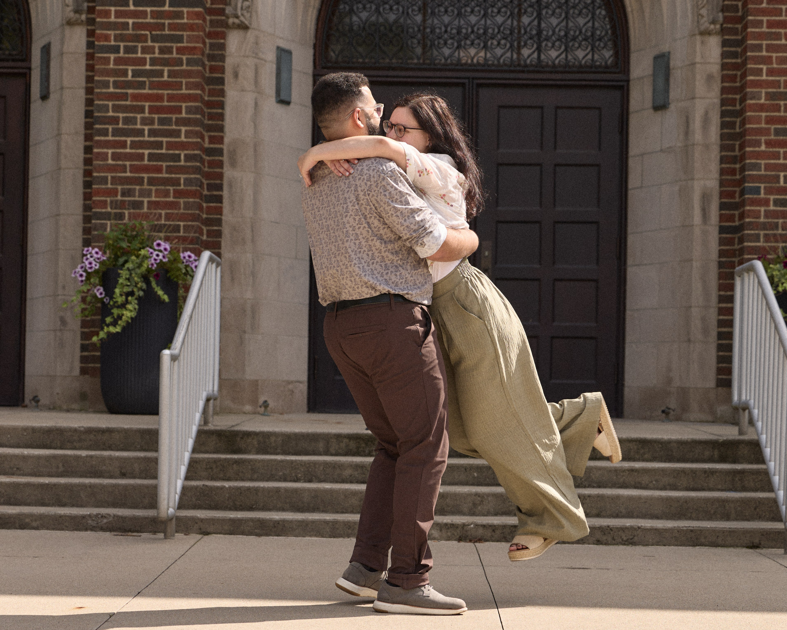 Groom lifting his fiancée on the steps of a brick building at Capital University in Columbus, Ohio