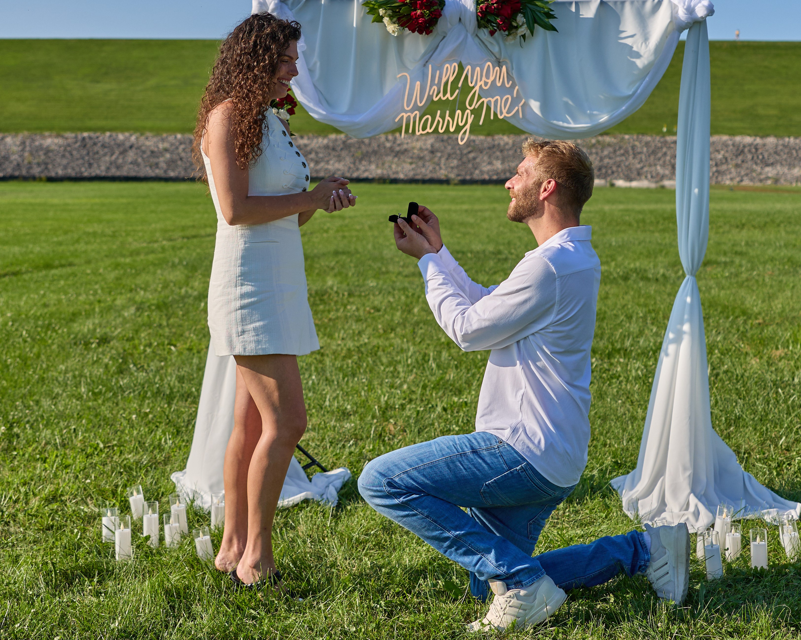 Proposal under a draped arch with a "Will you marry me?" sign in a field at Alum Creek, Ohio