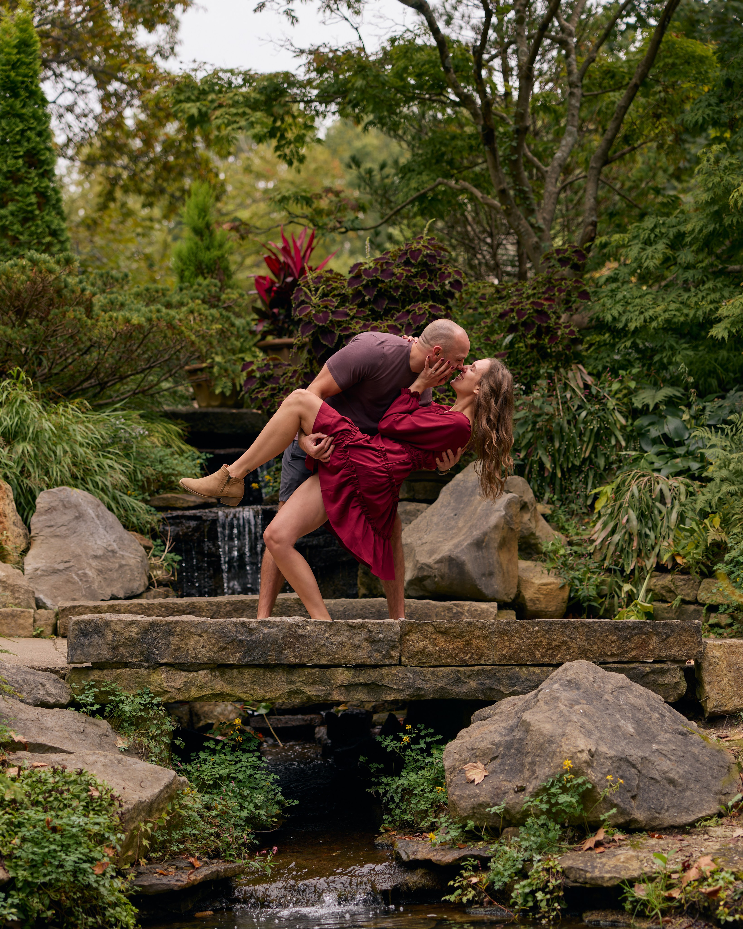 Playful embrace with her leg kicked up after a proposal at Inniswood Metro Gardens, Ohio