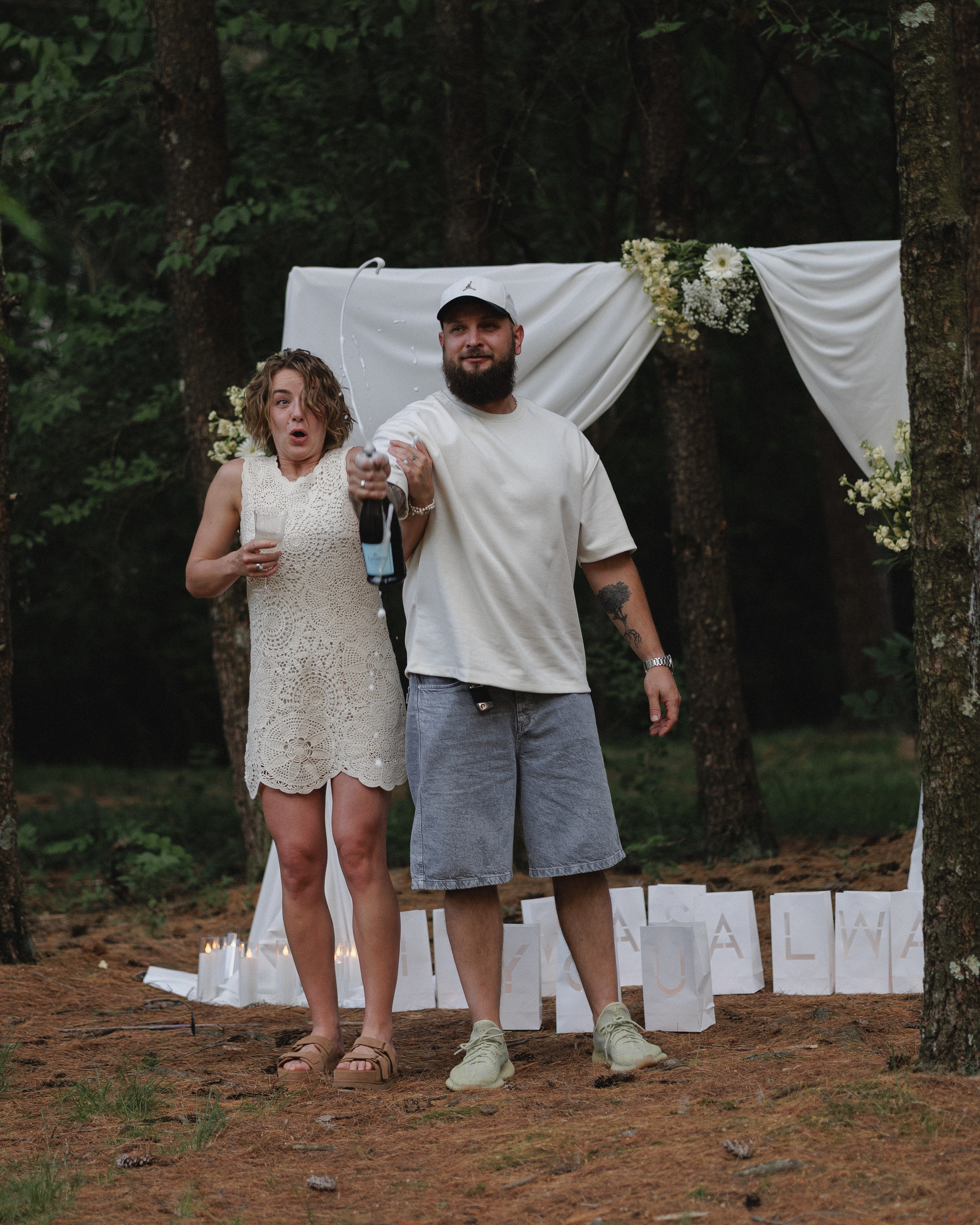 Couple with champagne bottles in a forest clearing near Columbus, Ohio