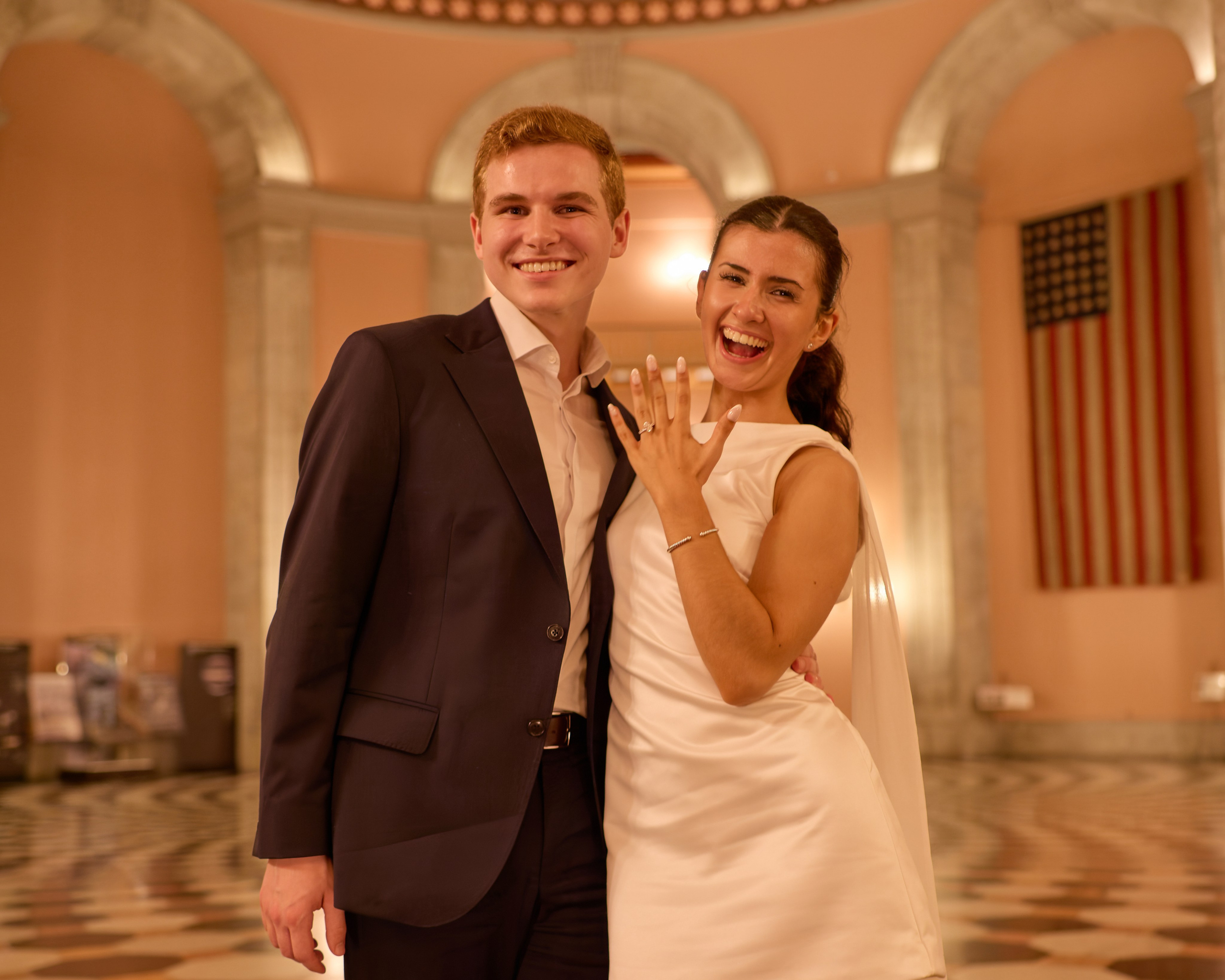 Couple portrait with the American flag behind at the Ohio Statehouse in Columbus, Ohio