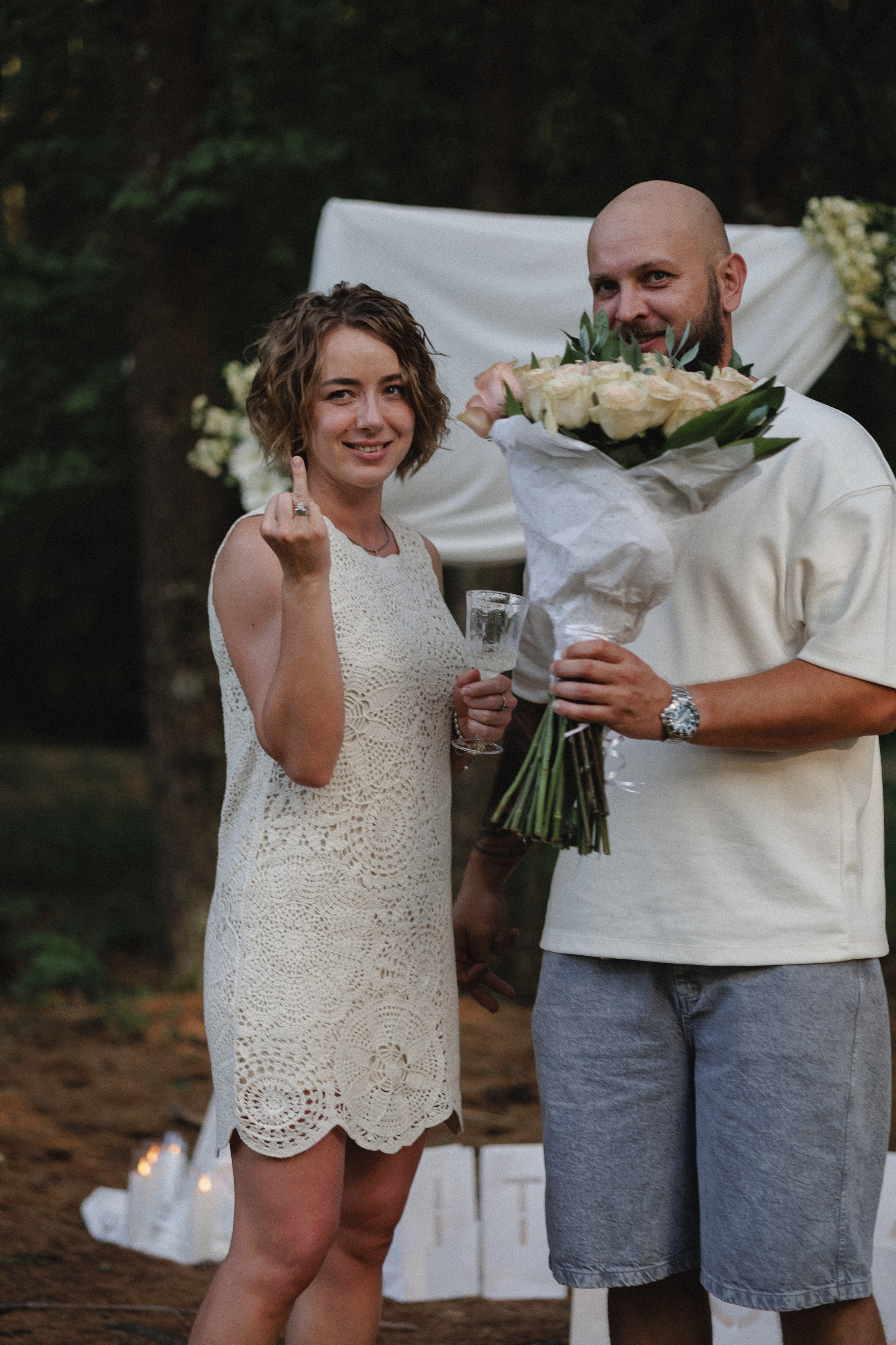She shows her ring while he holds the bouquet in the woods near Columbus, Ohio