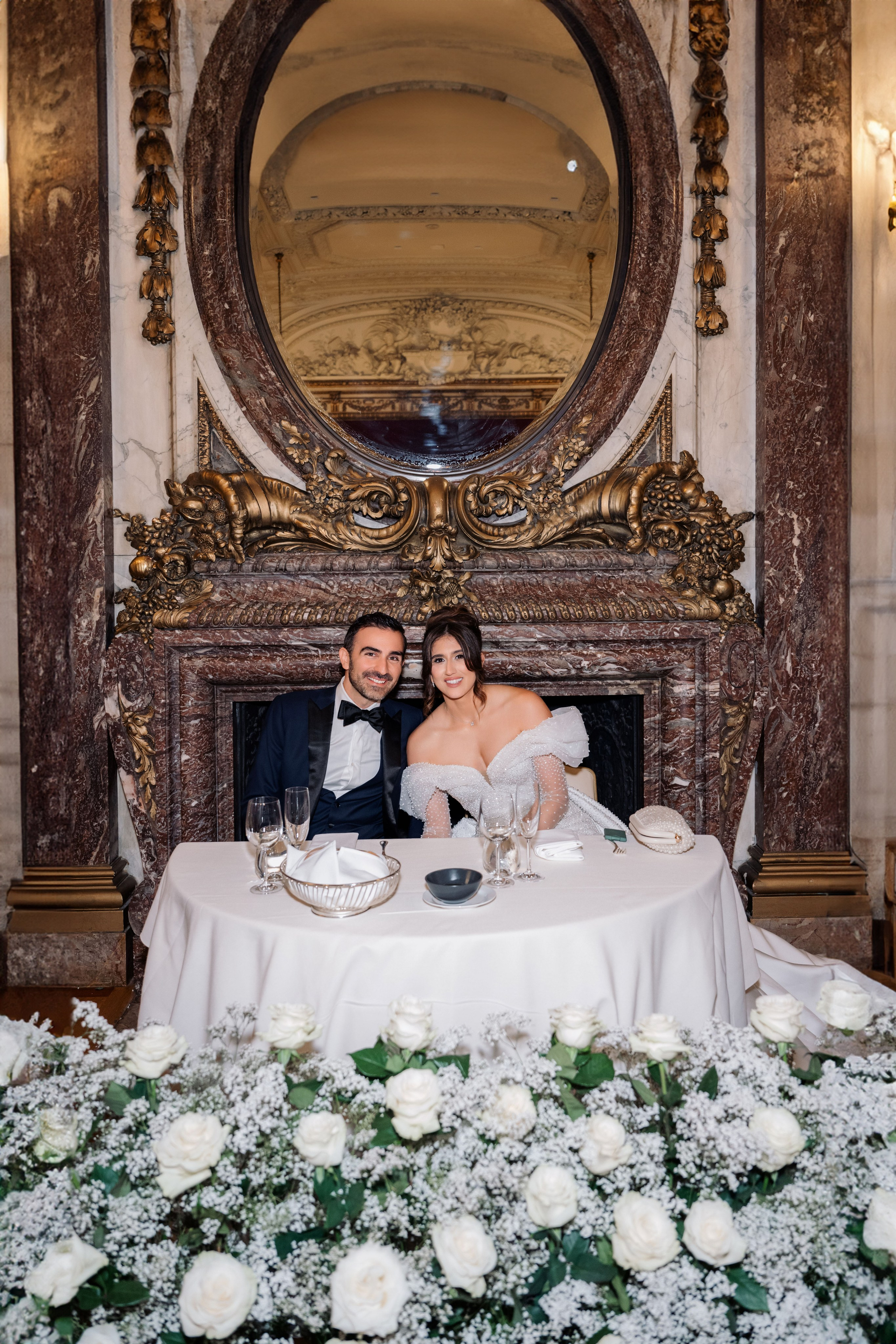 a bride and groom sitting at a table with flowers