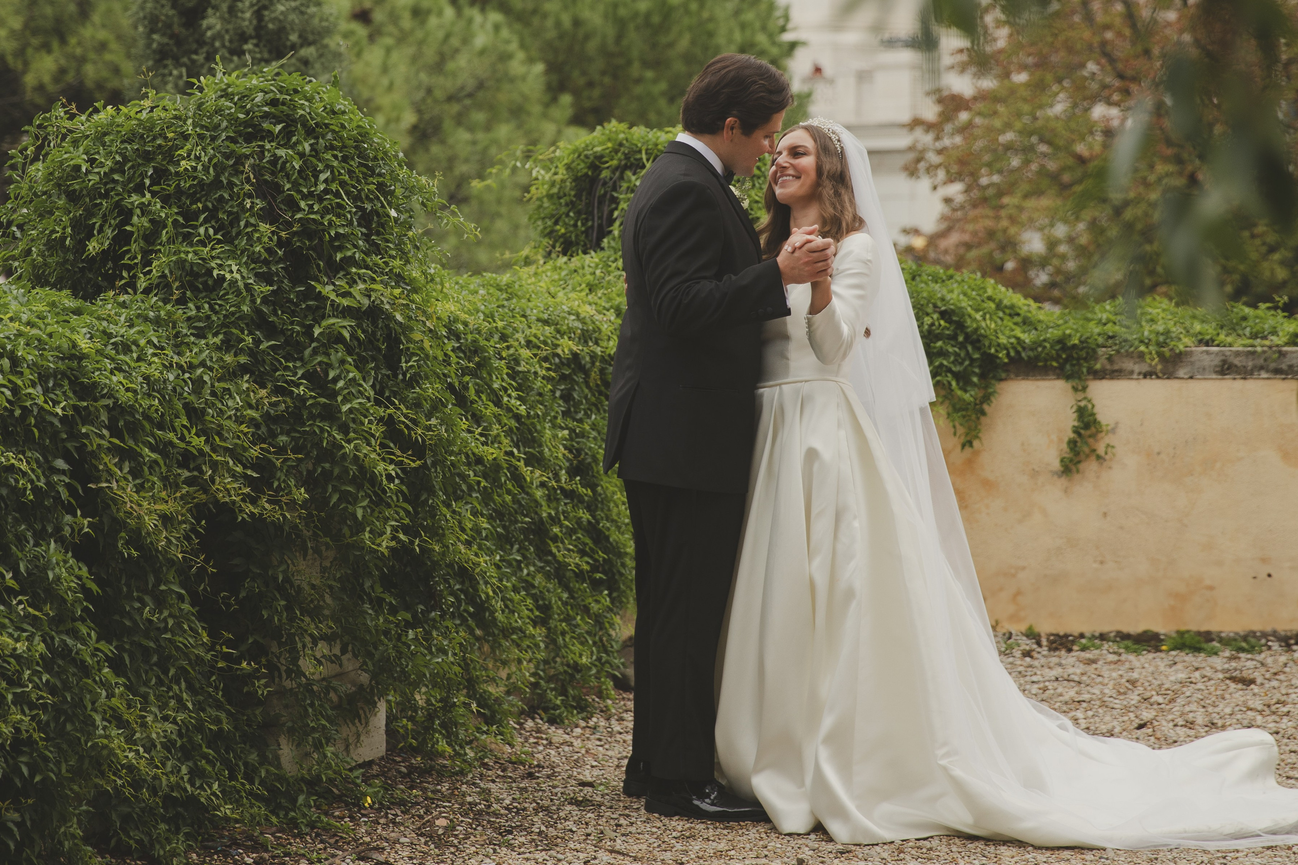 Newly married couple kissing in the luxury garden of a hotel overlooking Rome.