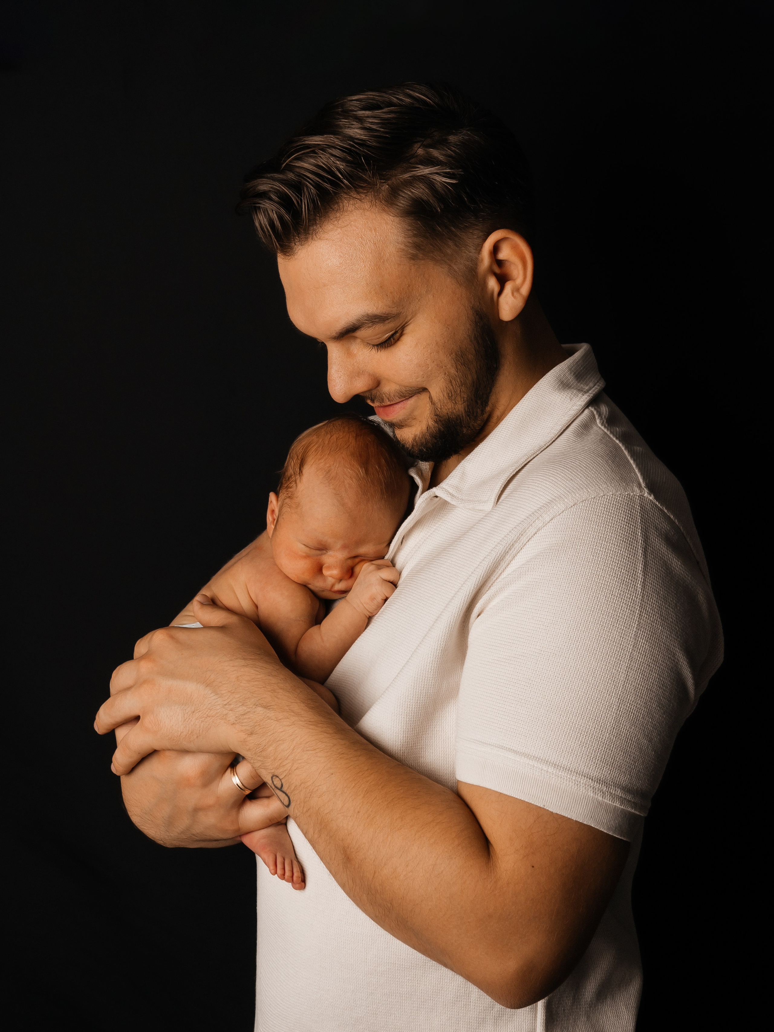 Familienfotoshooting zuhause. Vater hält sein Baby und genießt den gemeinsamen Moment