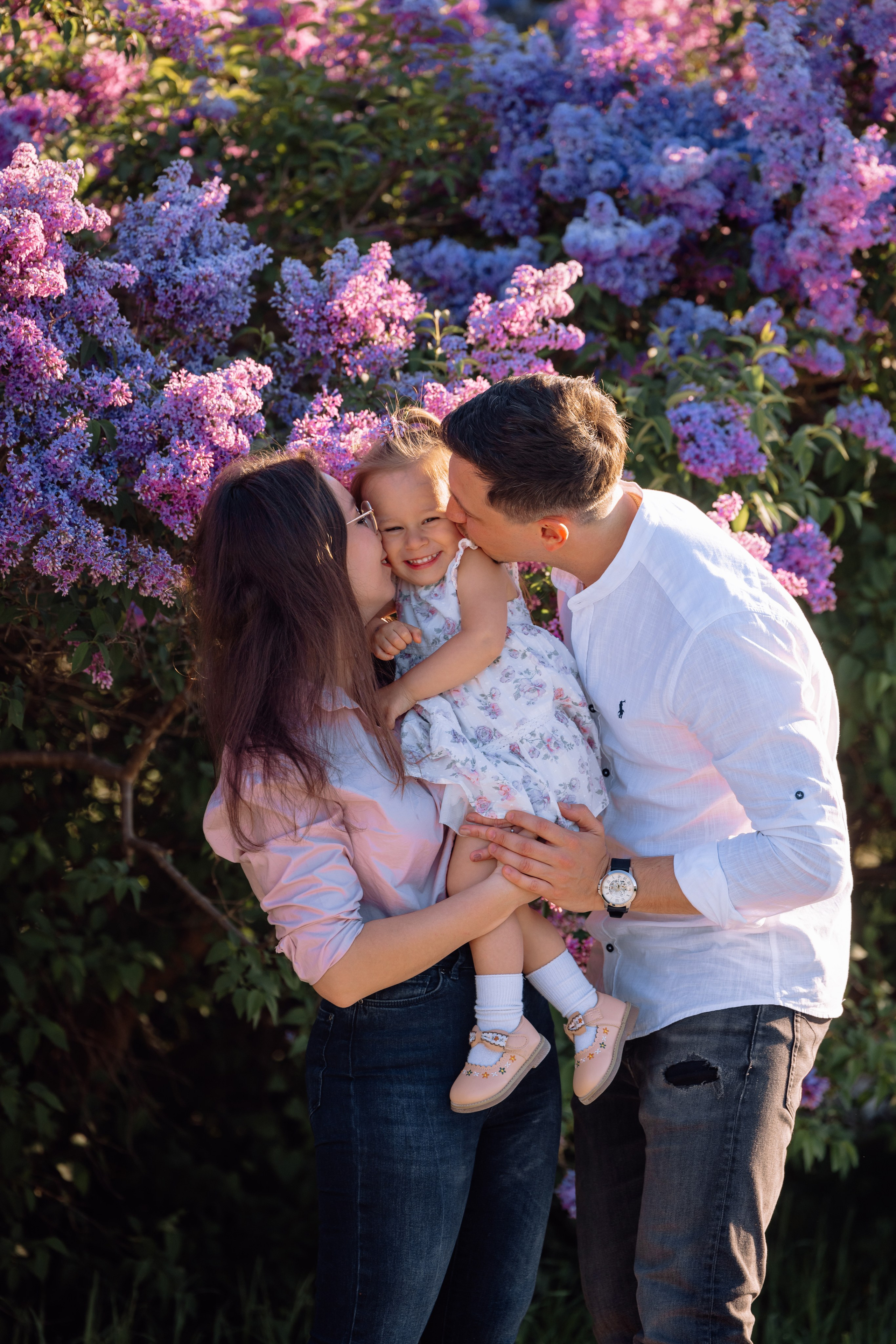 Mama und Papa küssen ihre Tochter beim Familienfotoshooting am Schloss Nymphenburg