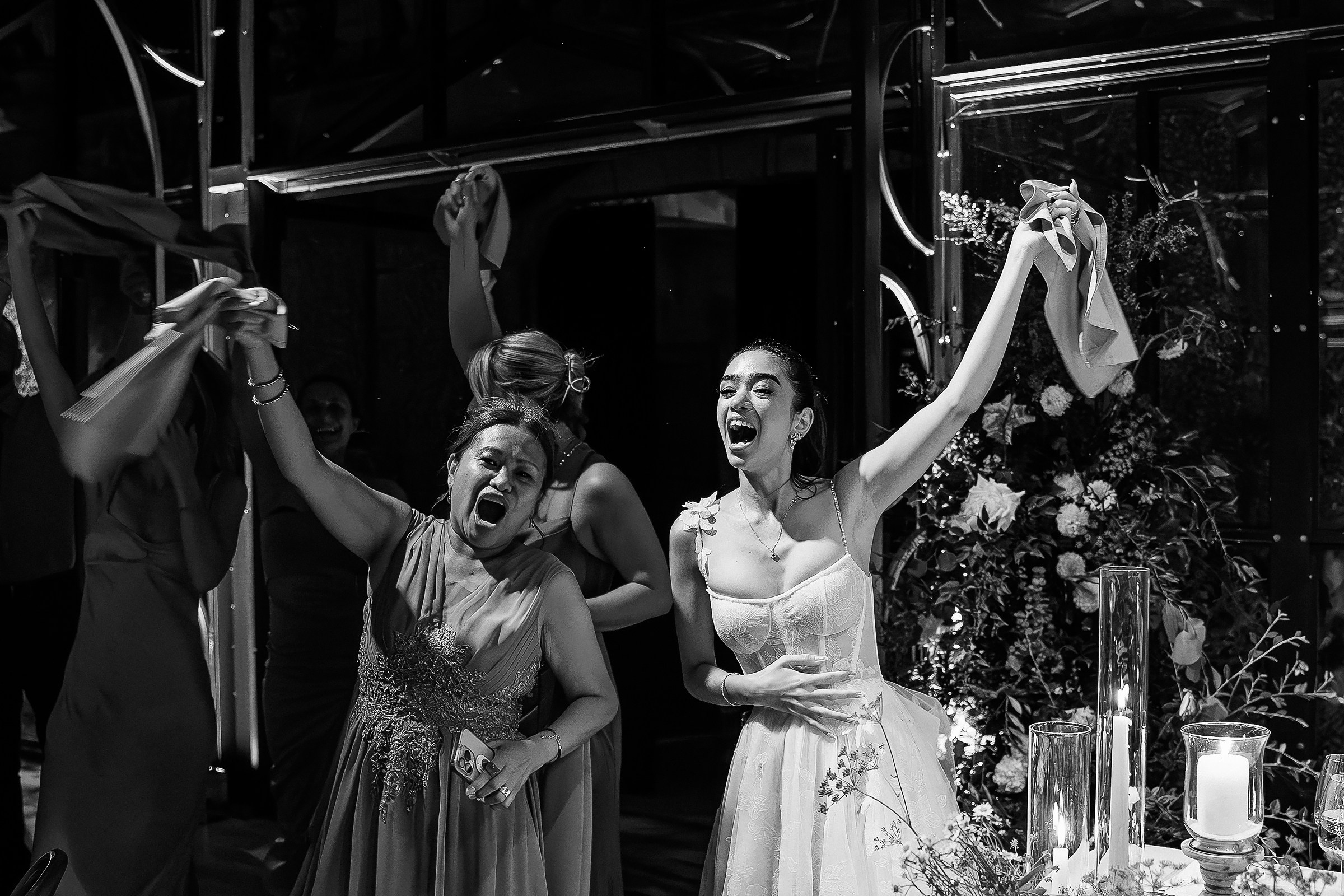 Bride and friend celebrating with joyful cheers, capturing pure wedding excitement.