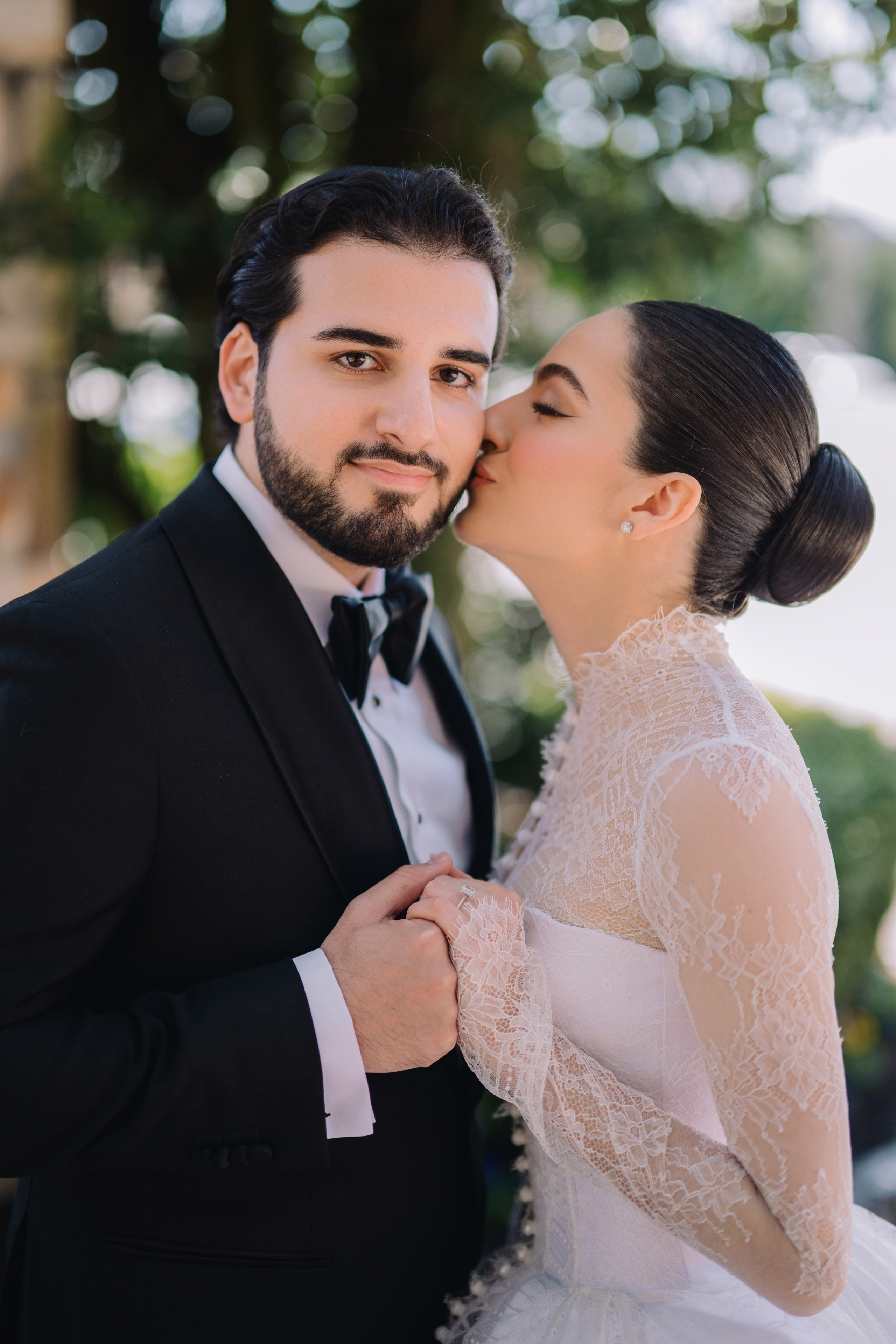 a bride and groom kissing in front of a tree
