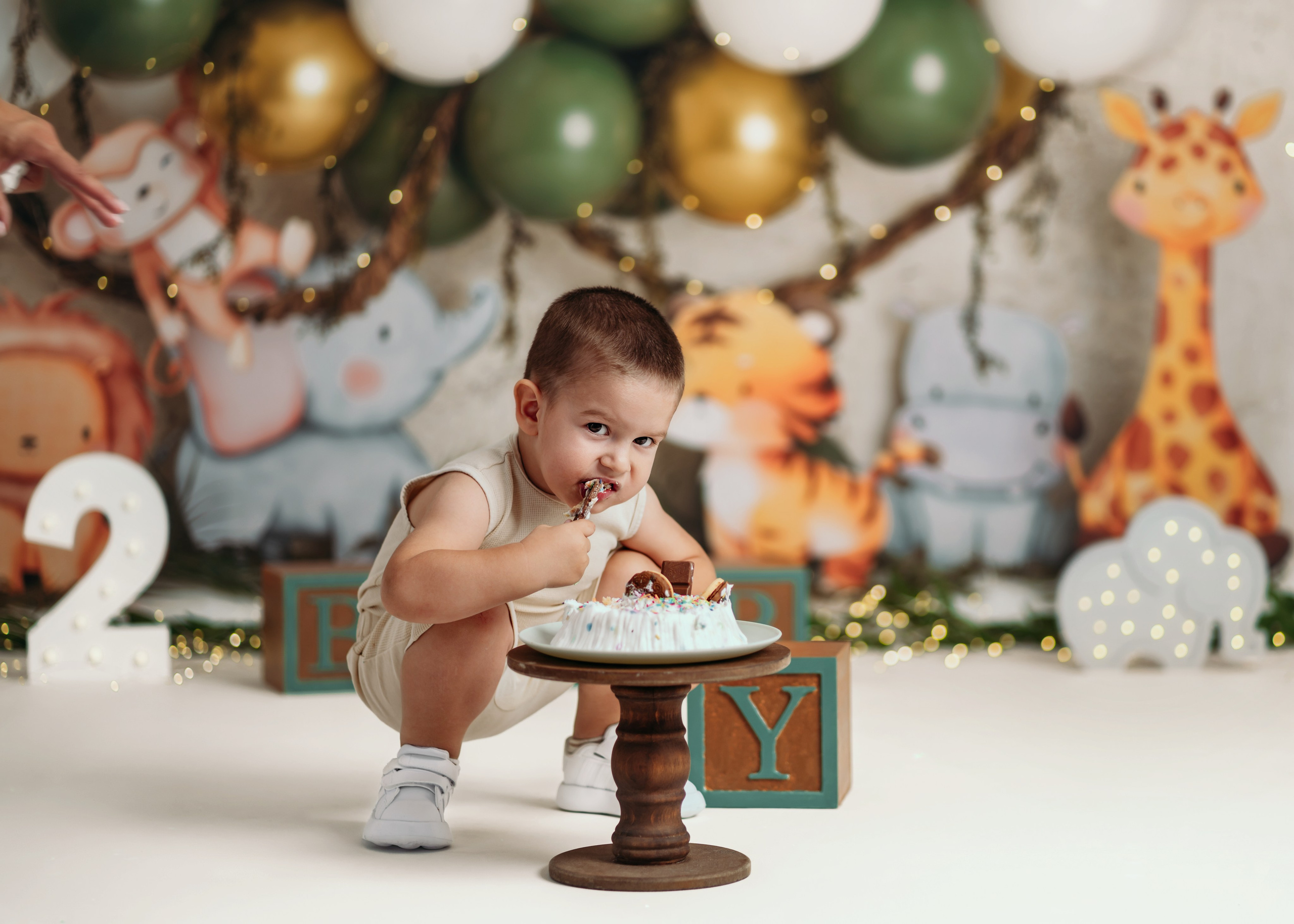 Beba sedi ispred dekoracije džungle tokom cake smash slikanja prvog rođendana