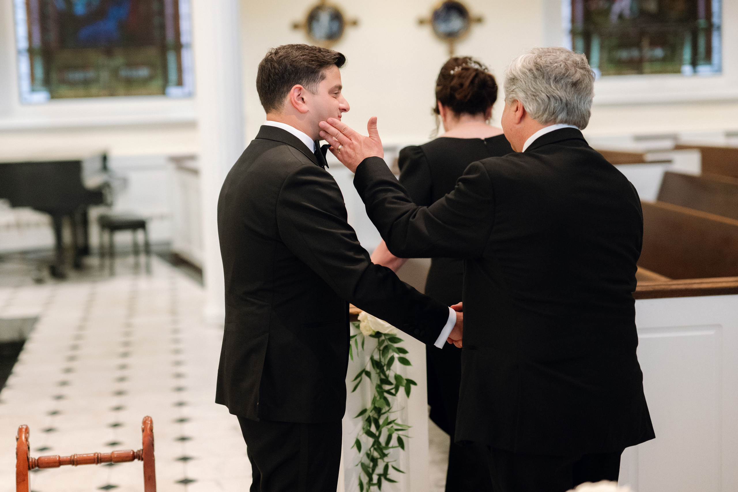 two men in suits are putting a tie on another man