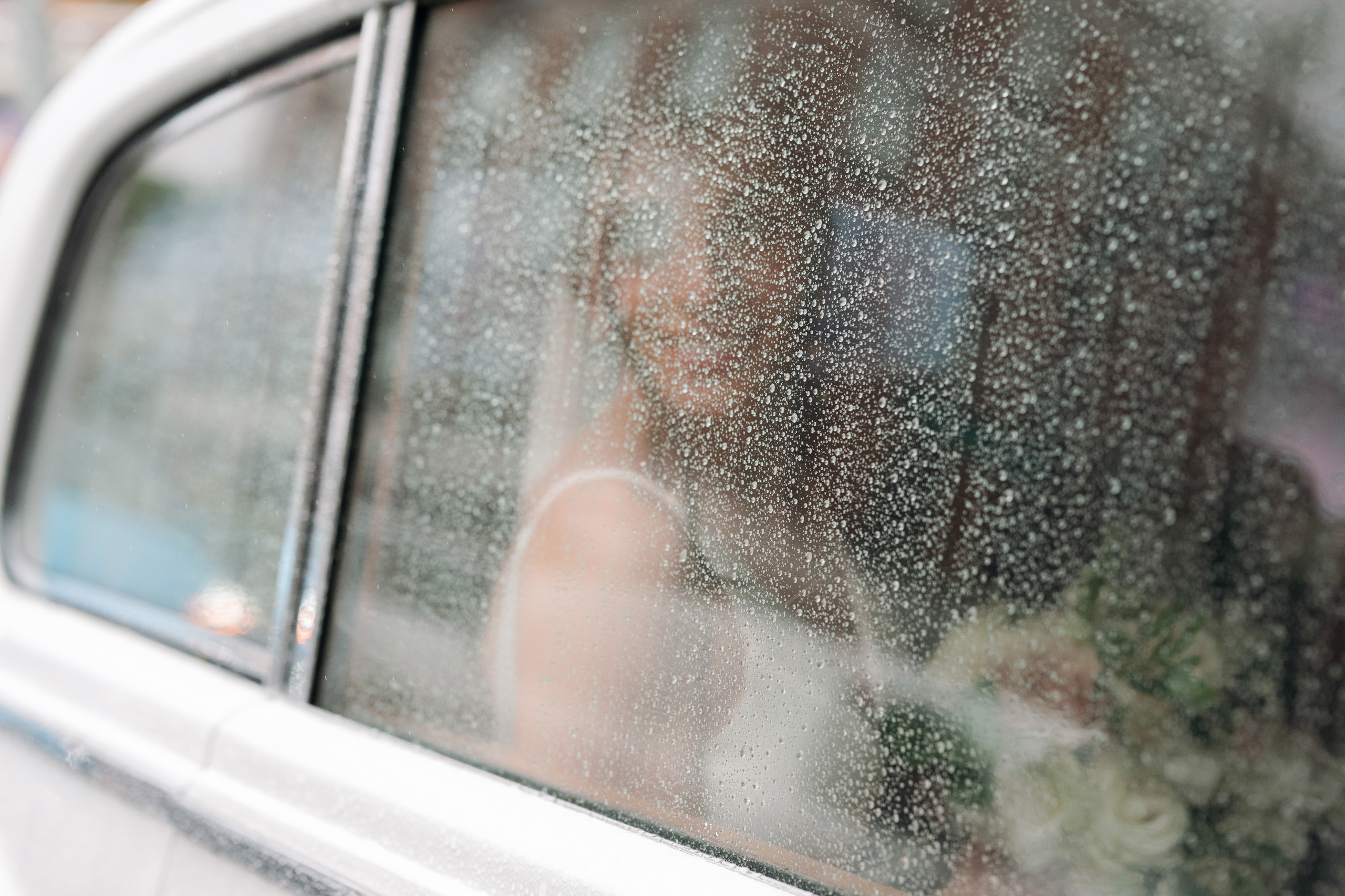 a white car with a window covered in rain
