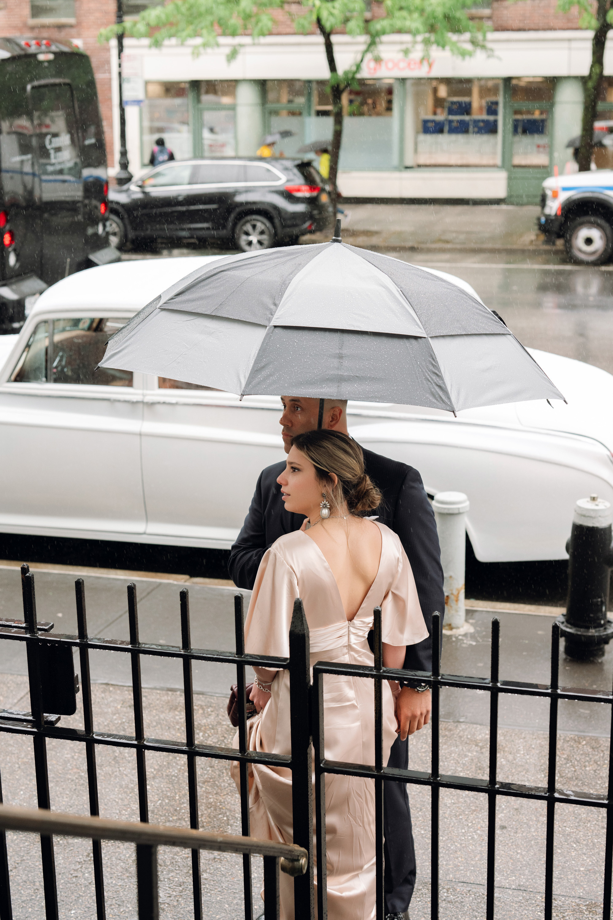 a man and woman standing on a sidewalk with an umbrella