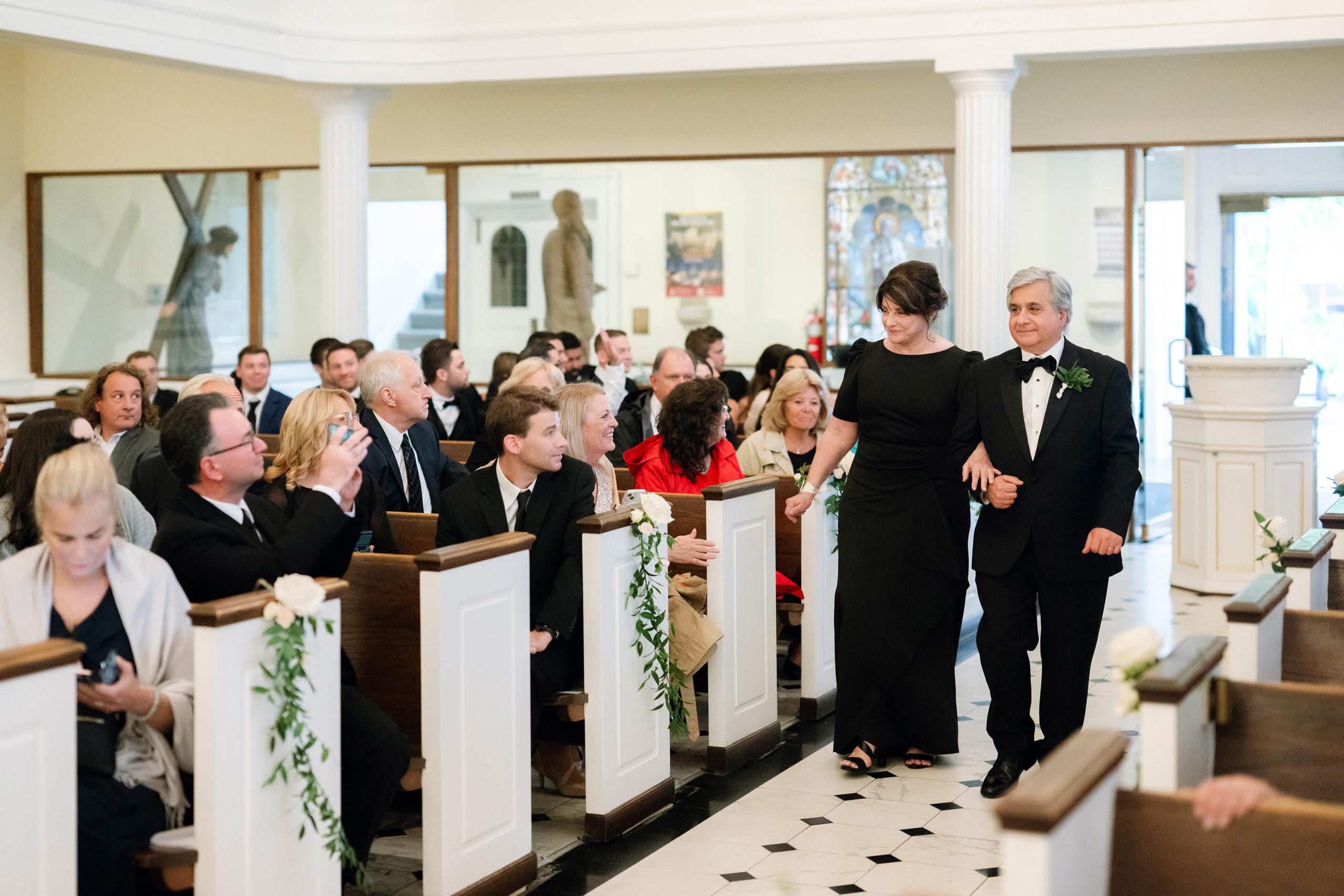 a man and woman walking down the aisle of a church