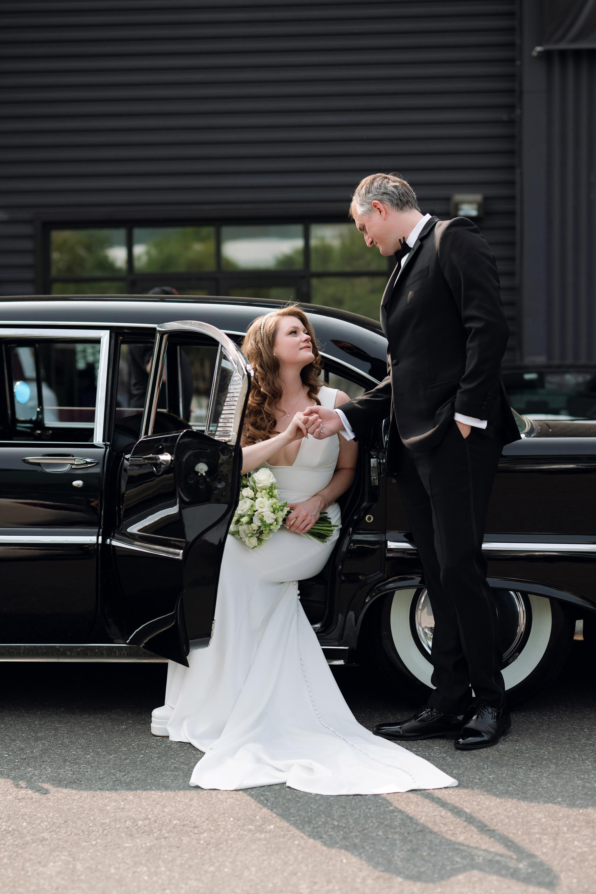 a bride and groom getting into a black car