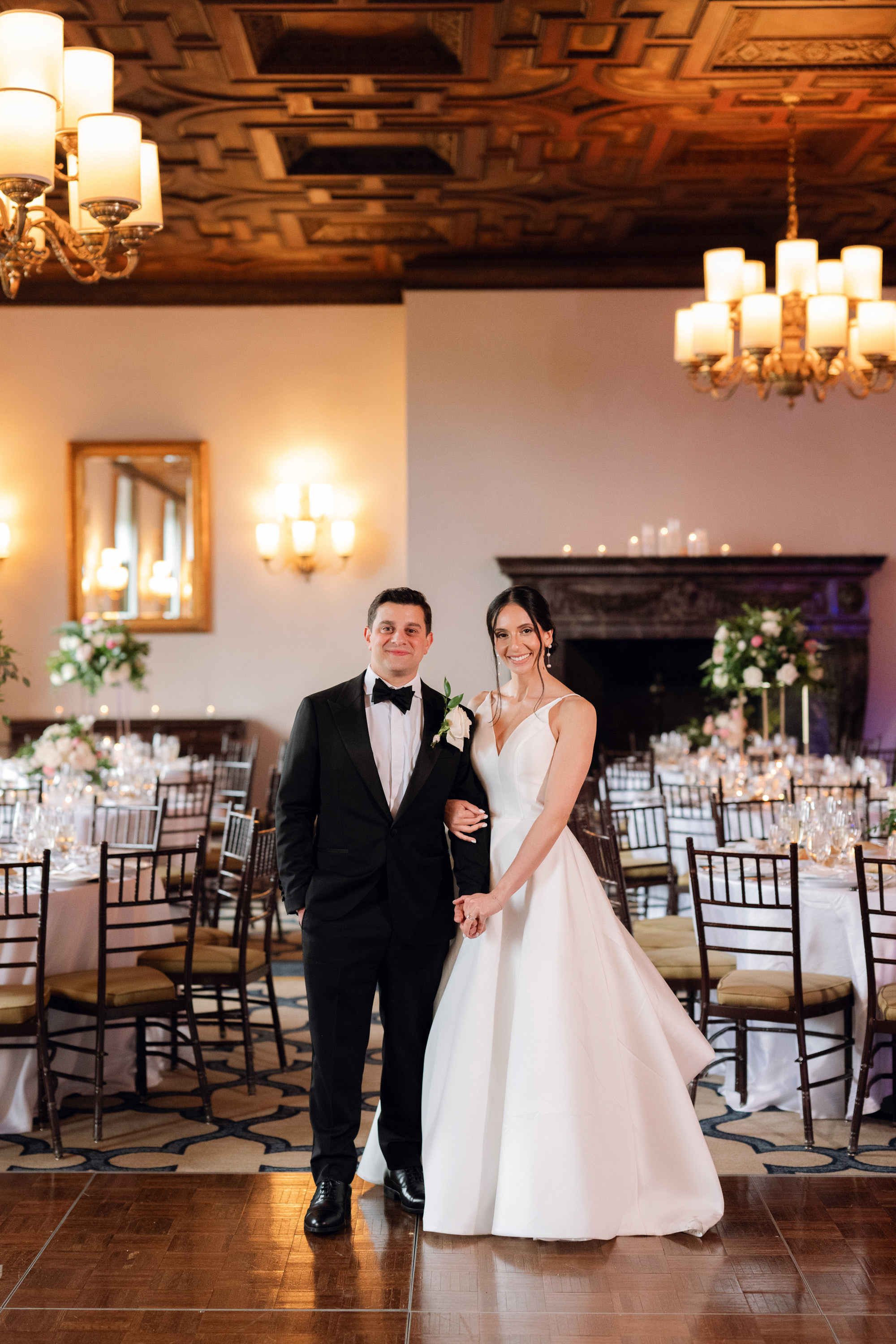 a bride and groom pose for a photo in a ballroom