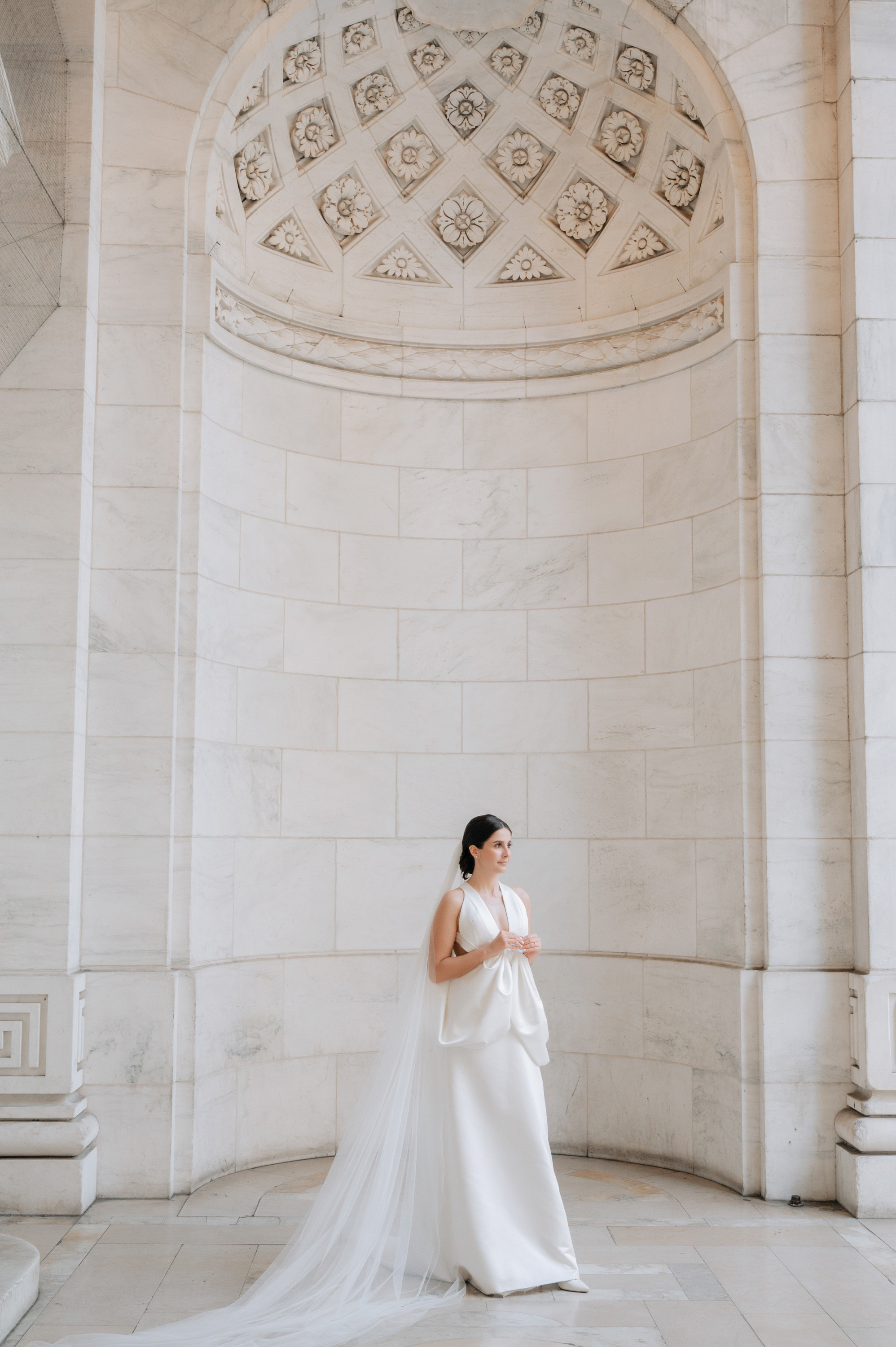 a bride in a white wedding dress standing in front of a stone wall