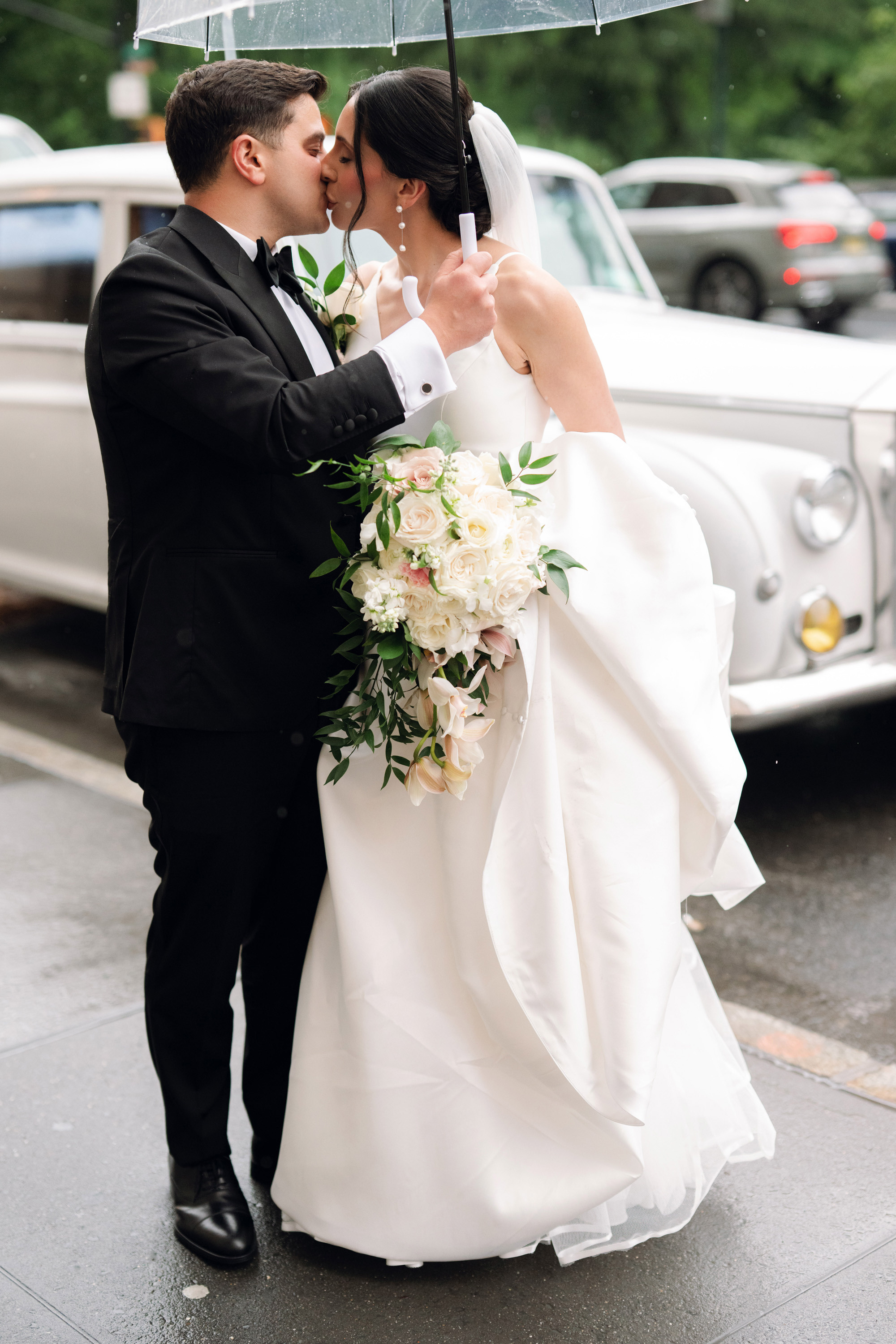 a bride and groom kissing under an umbrella