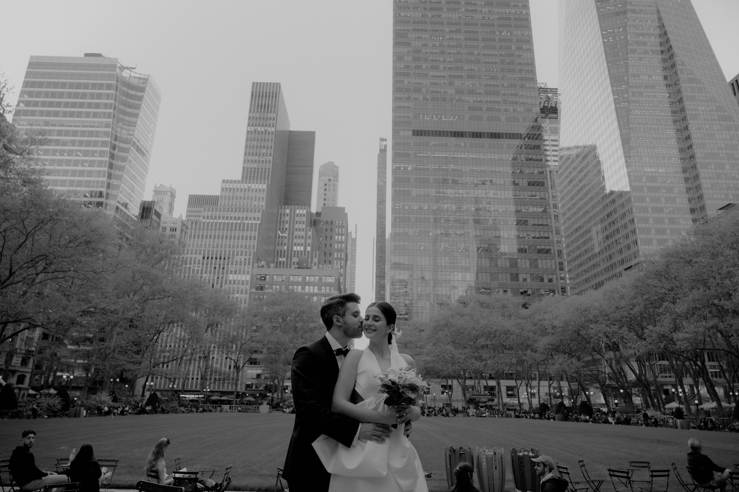 a bride and groom pose for a photo in front of the city skyline