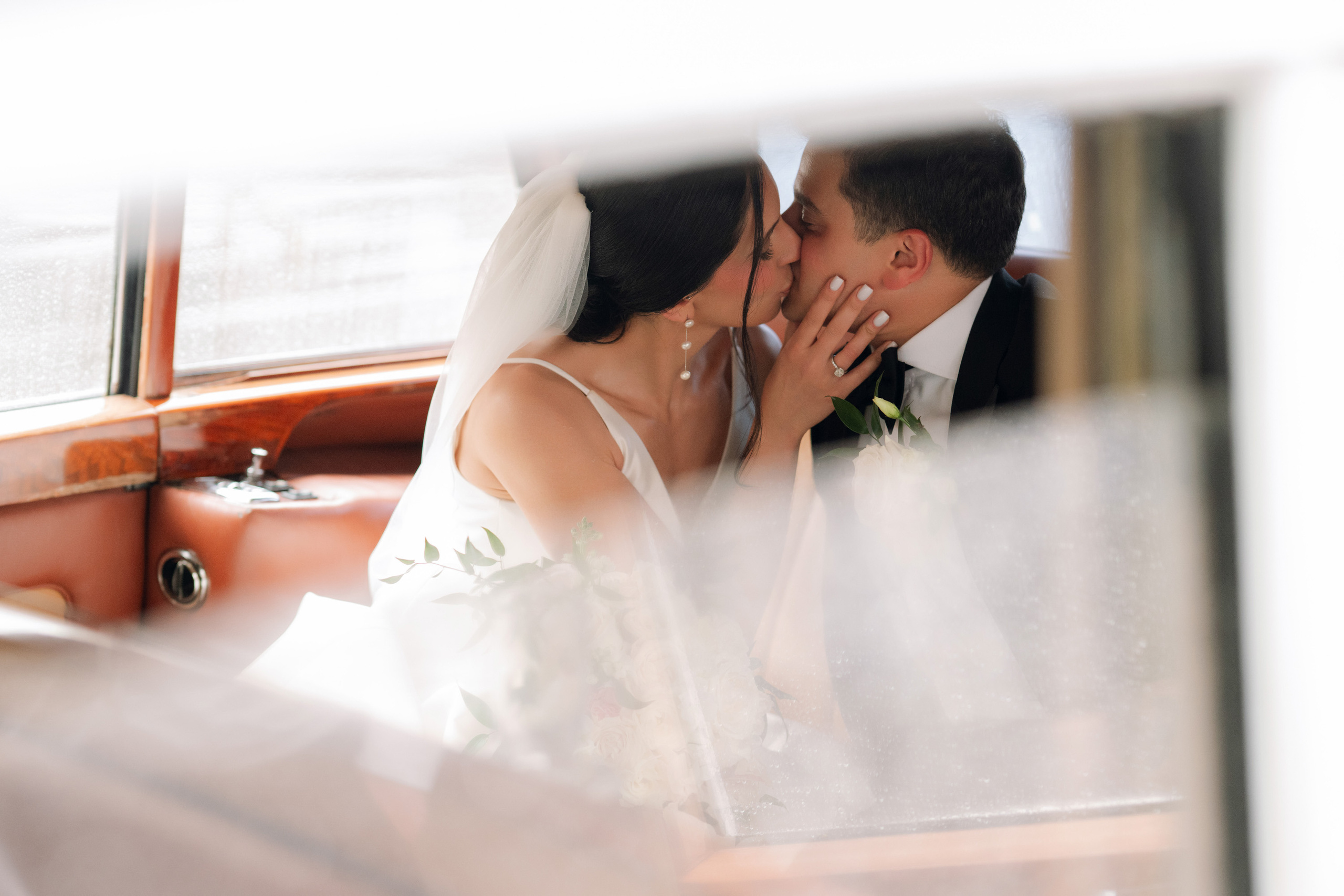 a bride and groom kissing in a car