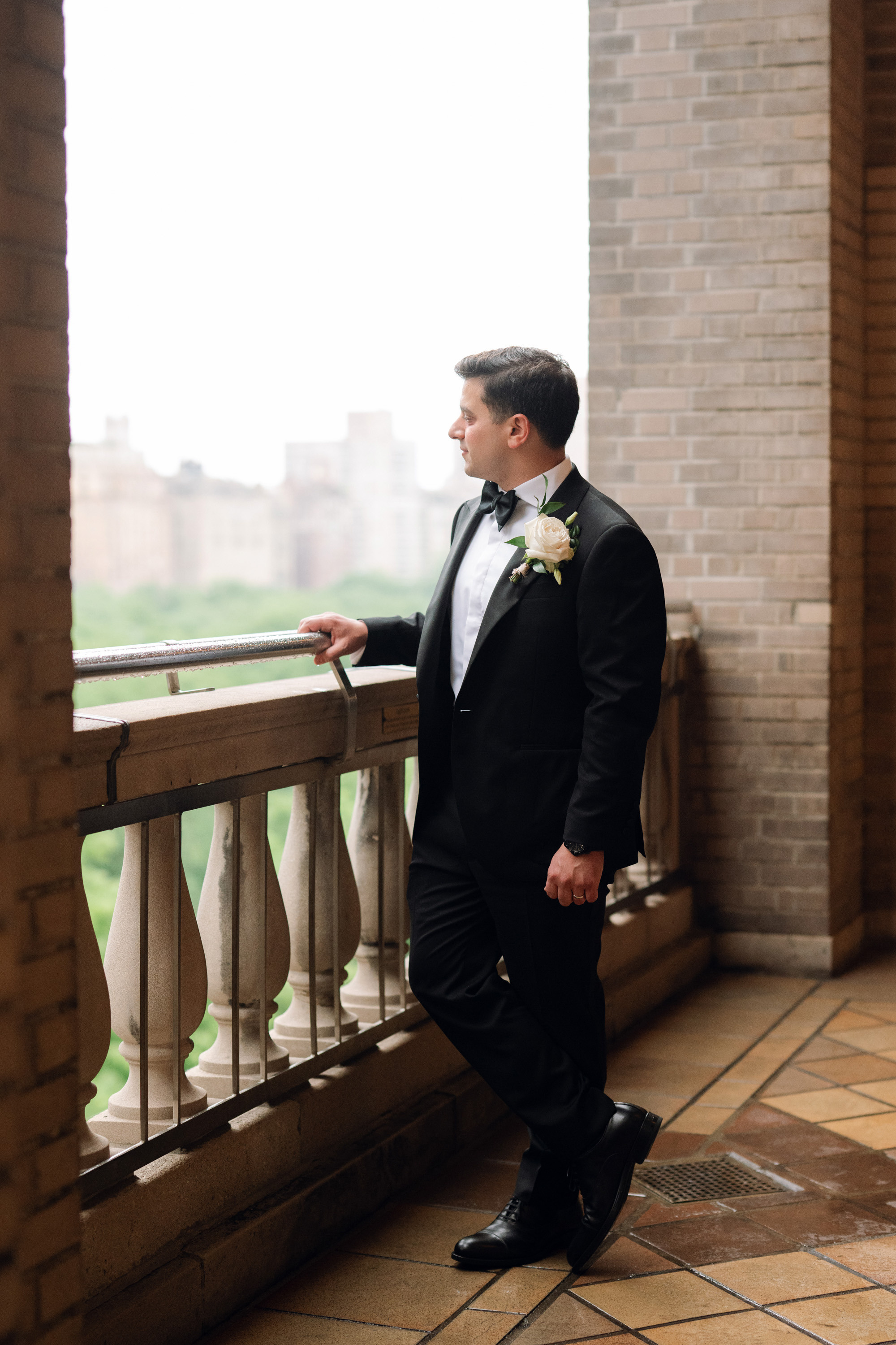 a man in a suit and bow tie standing on a balcony