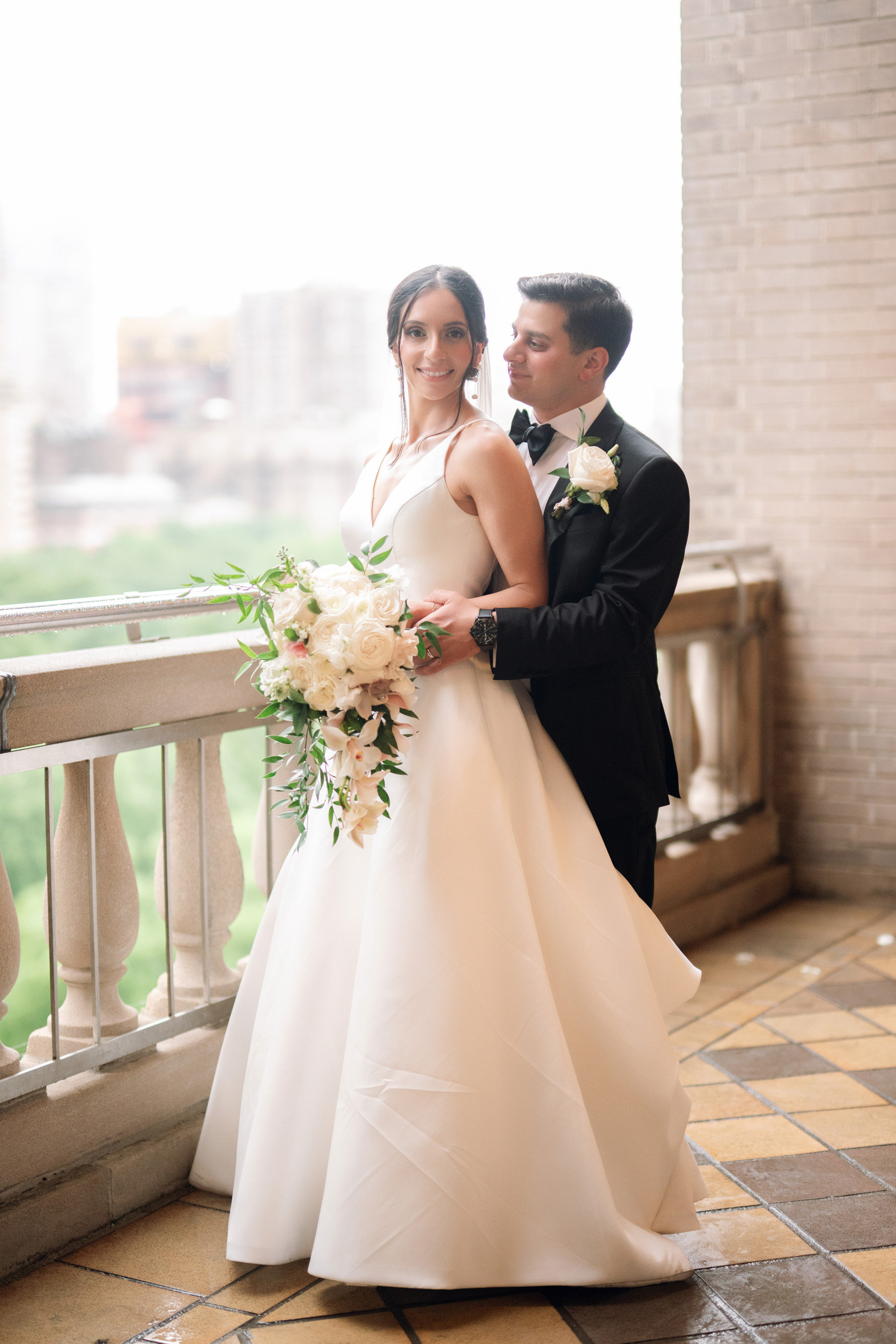 a bride and groom pose for a photo on the balcony of their wedding venue