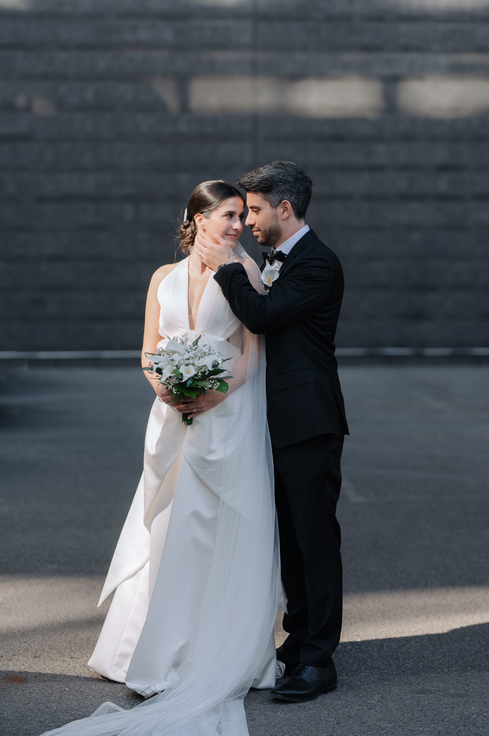 a bride and groom pose for a photo in front of a brick wall