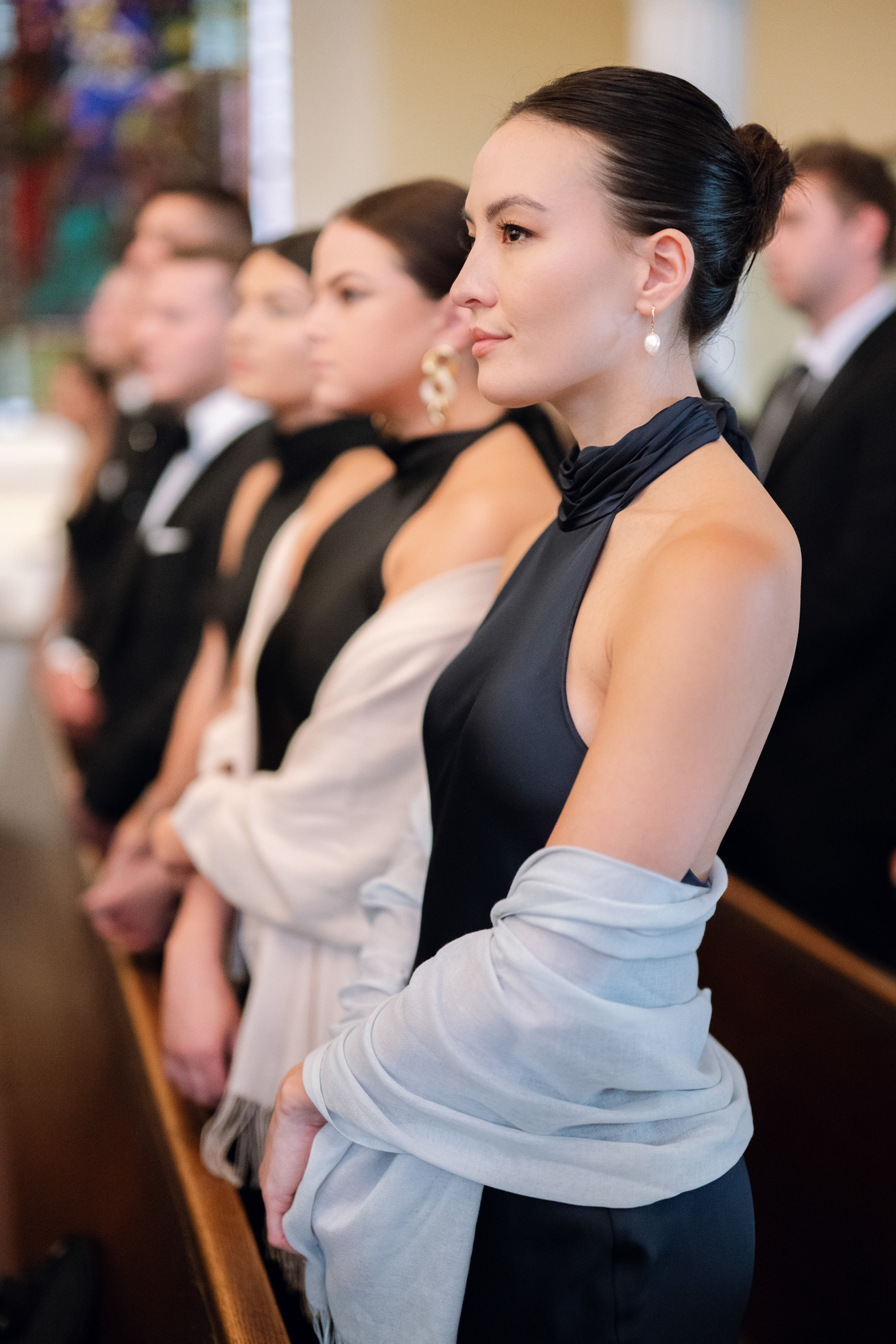 a woman in a black dress sitting in a pew