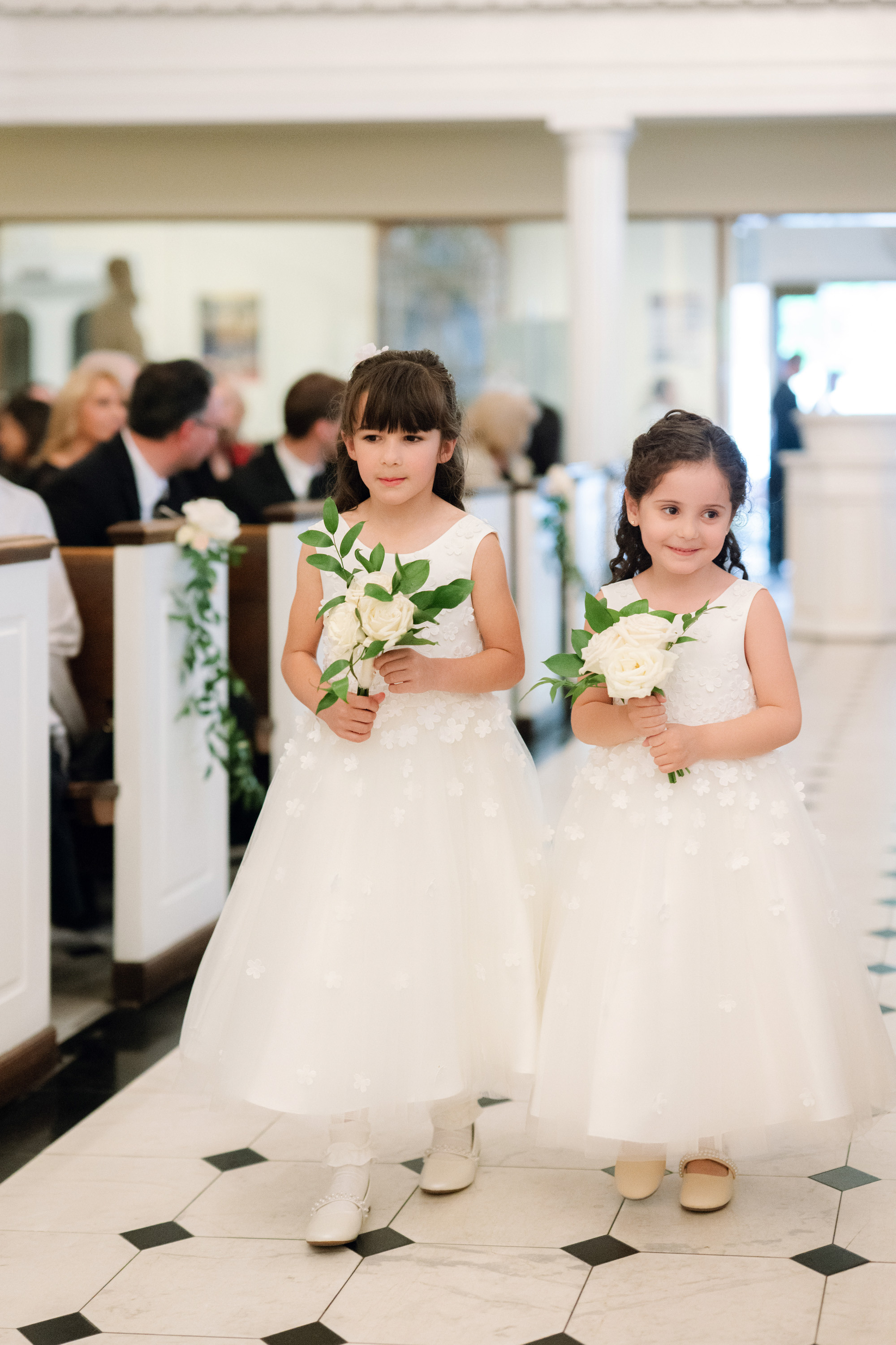 two little girls in white dresses holding flowers