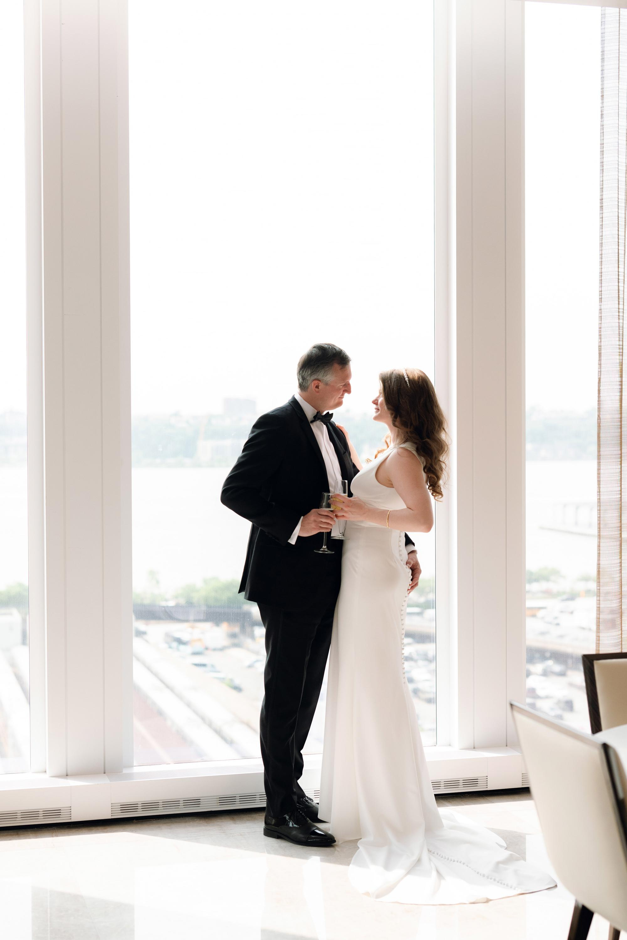 a bride and groom standing in front of a window