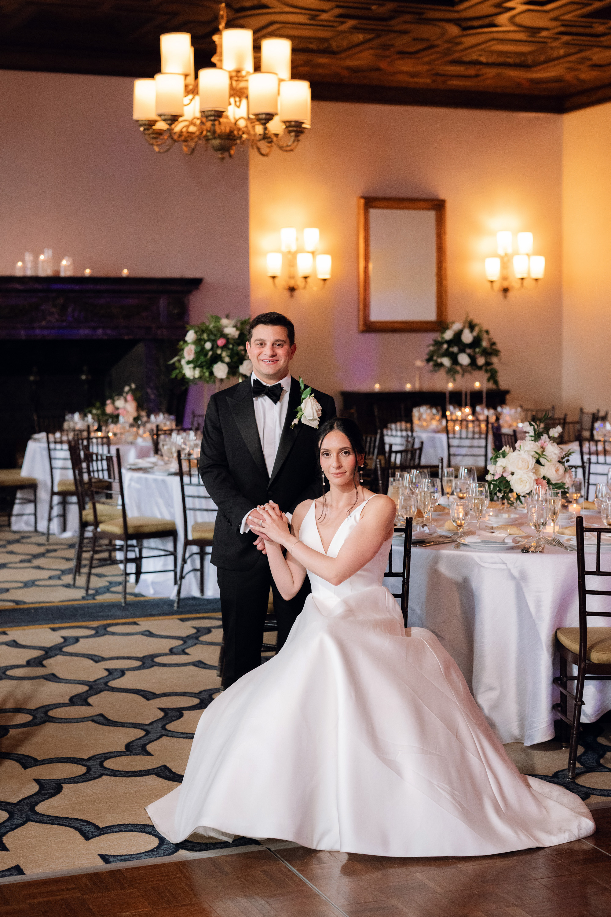 a bride and groom pose for a photo in the ballroom