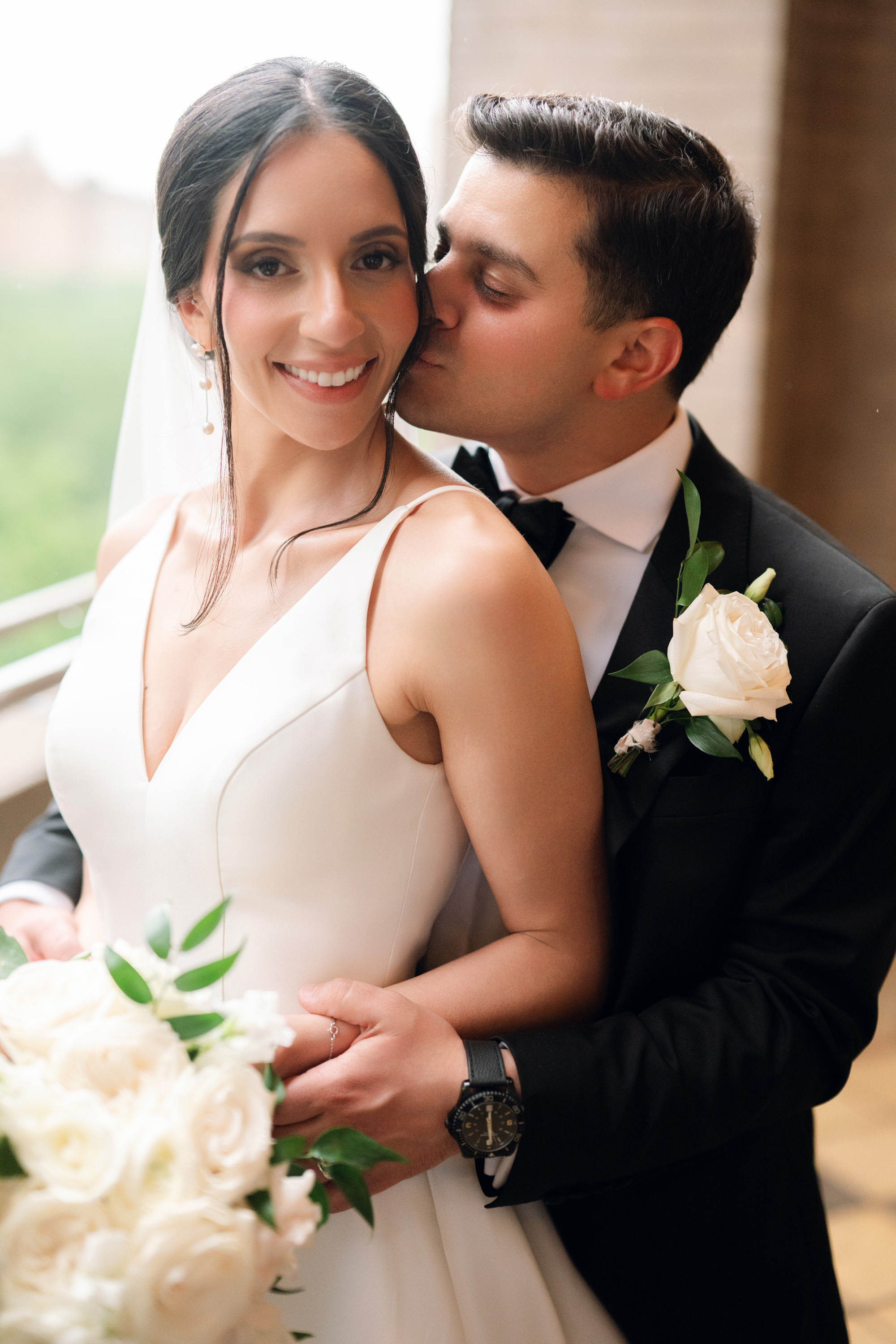 a bride and groom kissing on a balcony