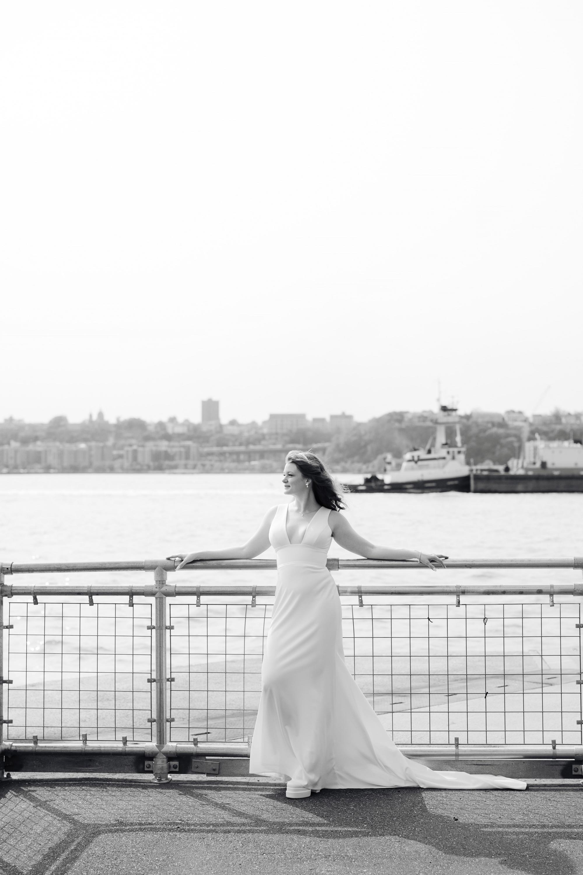 a bride standing on a bridge overlooking the water