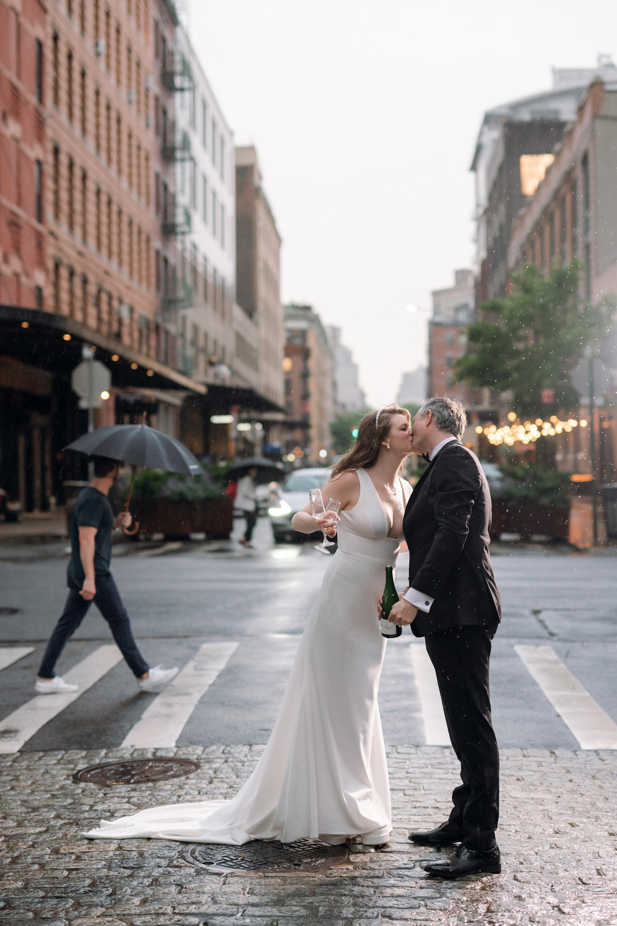 a bride and groom kissing on a rainy day