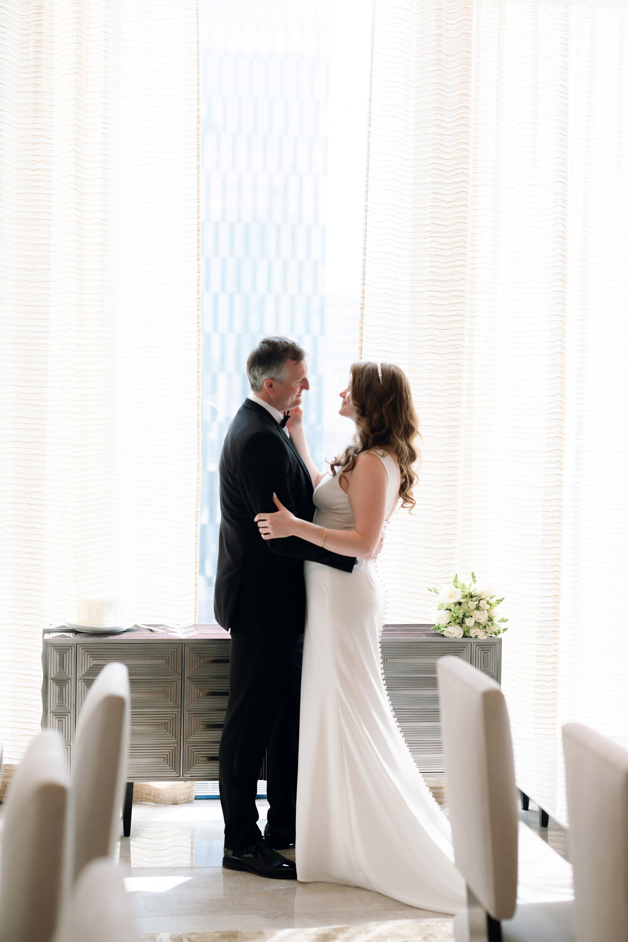 a bride and groom are standing in front of a window