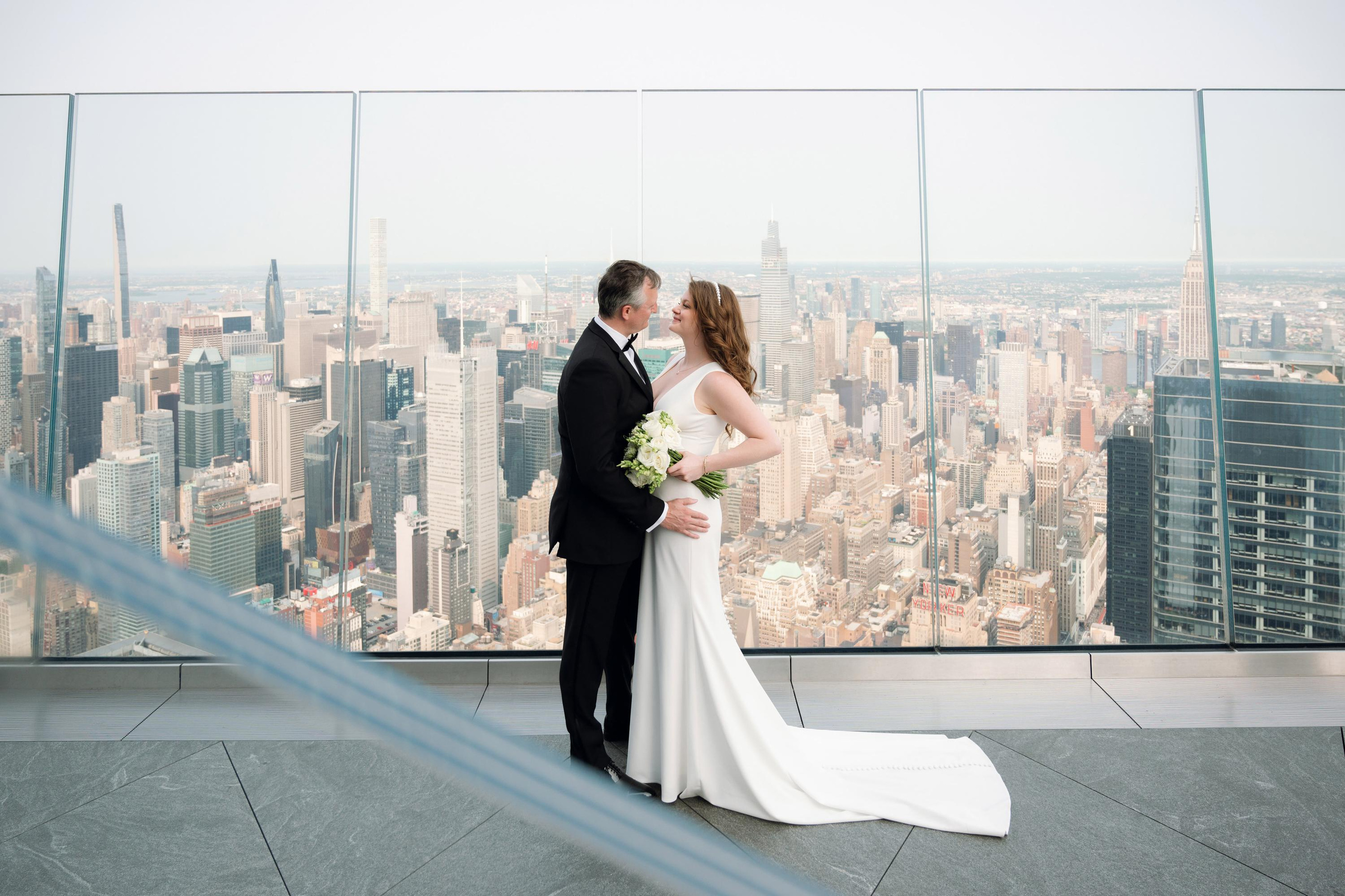 a bride and groom pose for a photo in front of the empire building