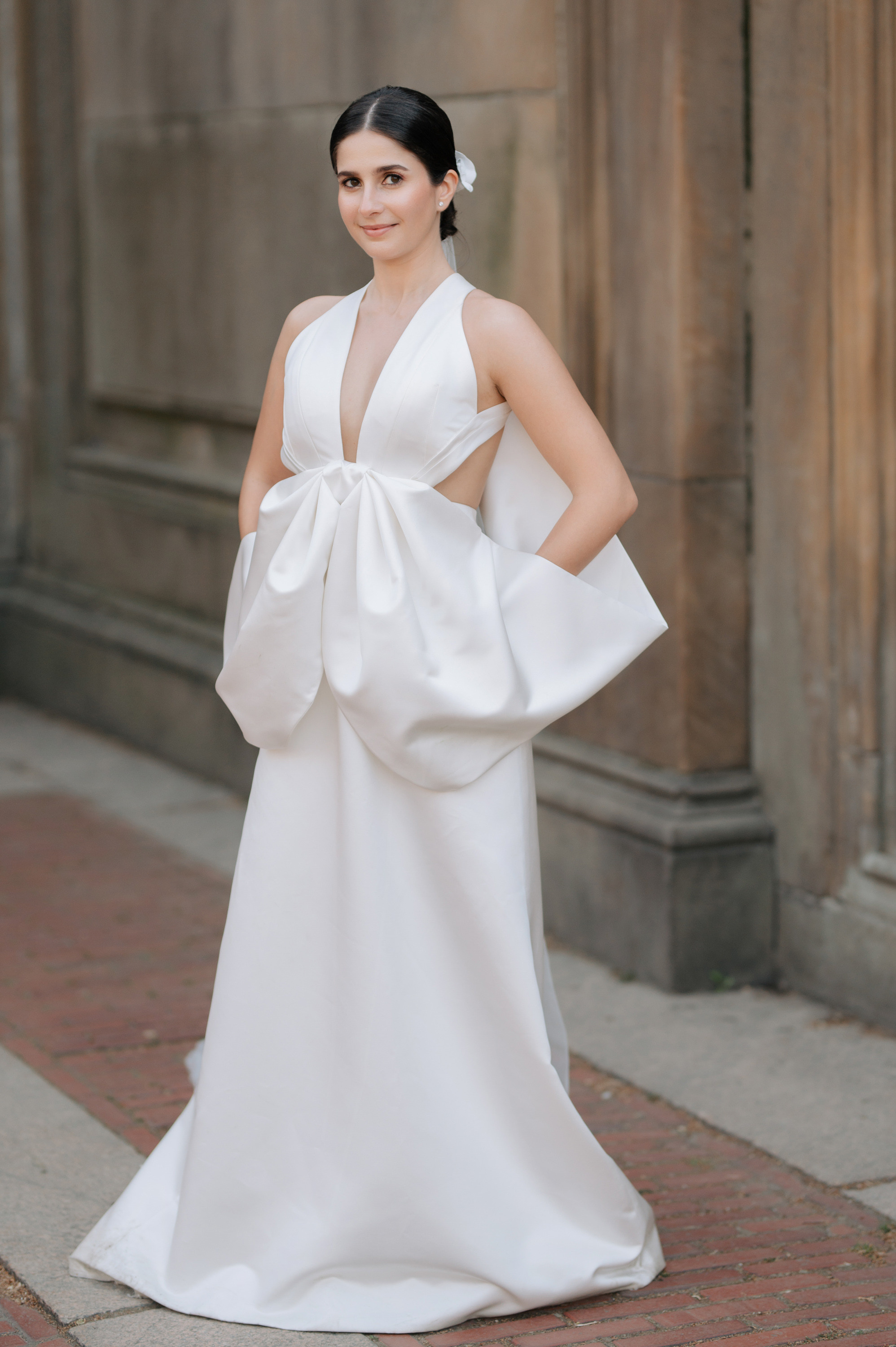 a woman in a white dress standing on a brick sidewalk