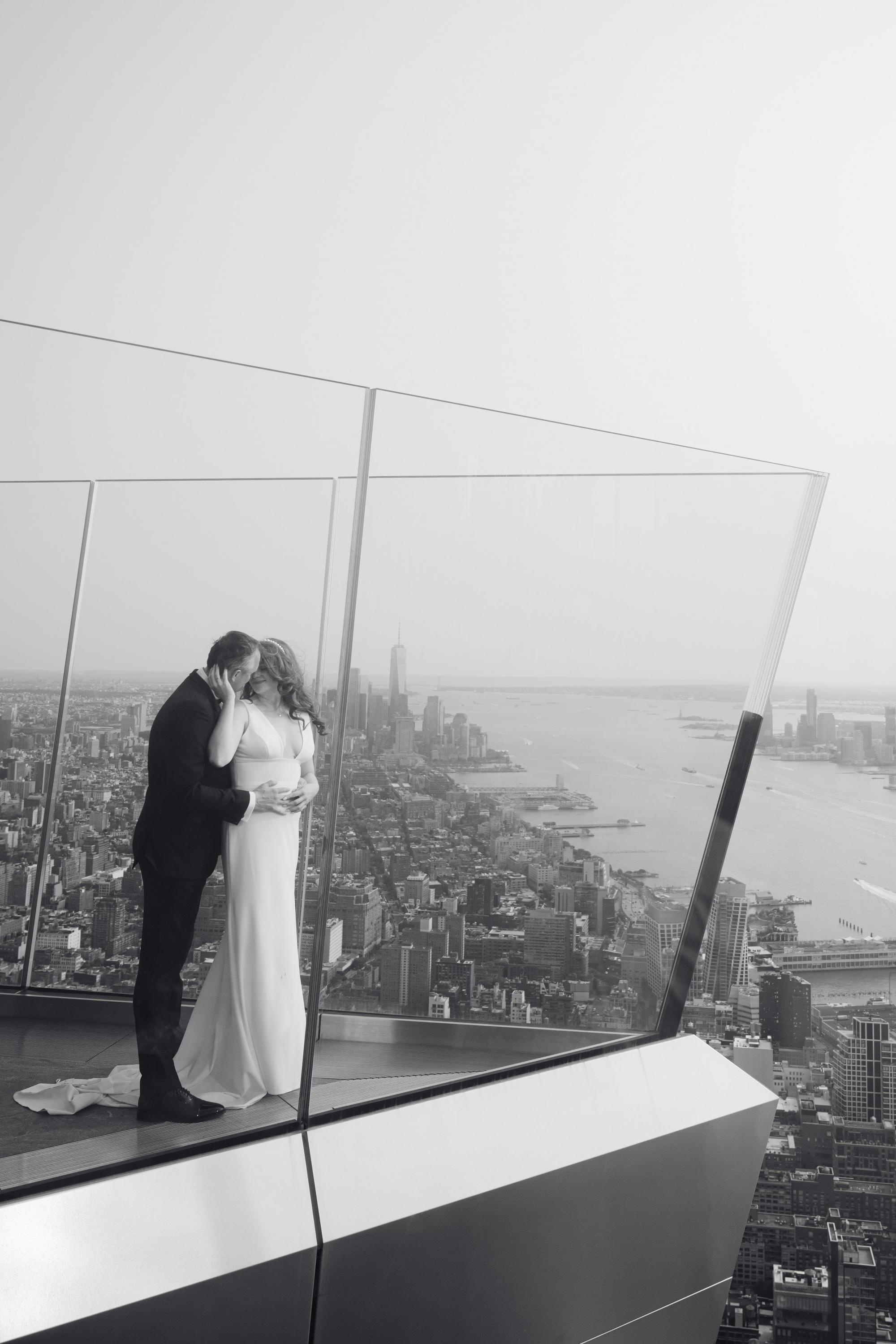 a bride and groom kissing on the top of the empire building