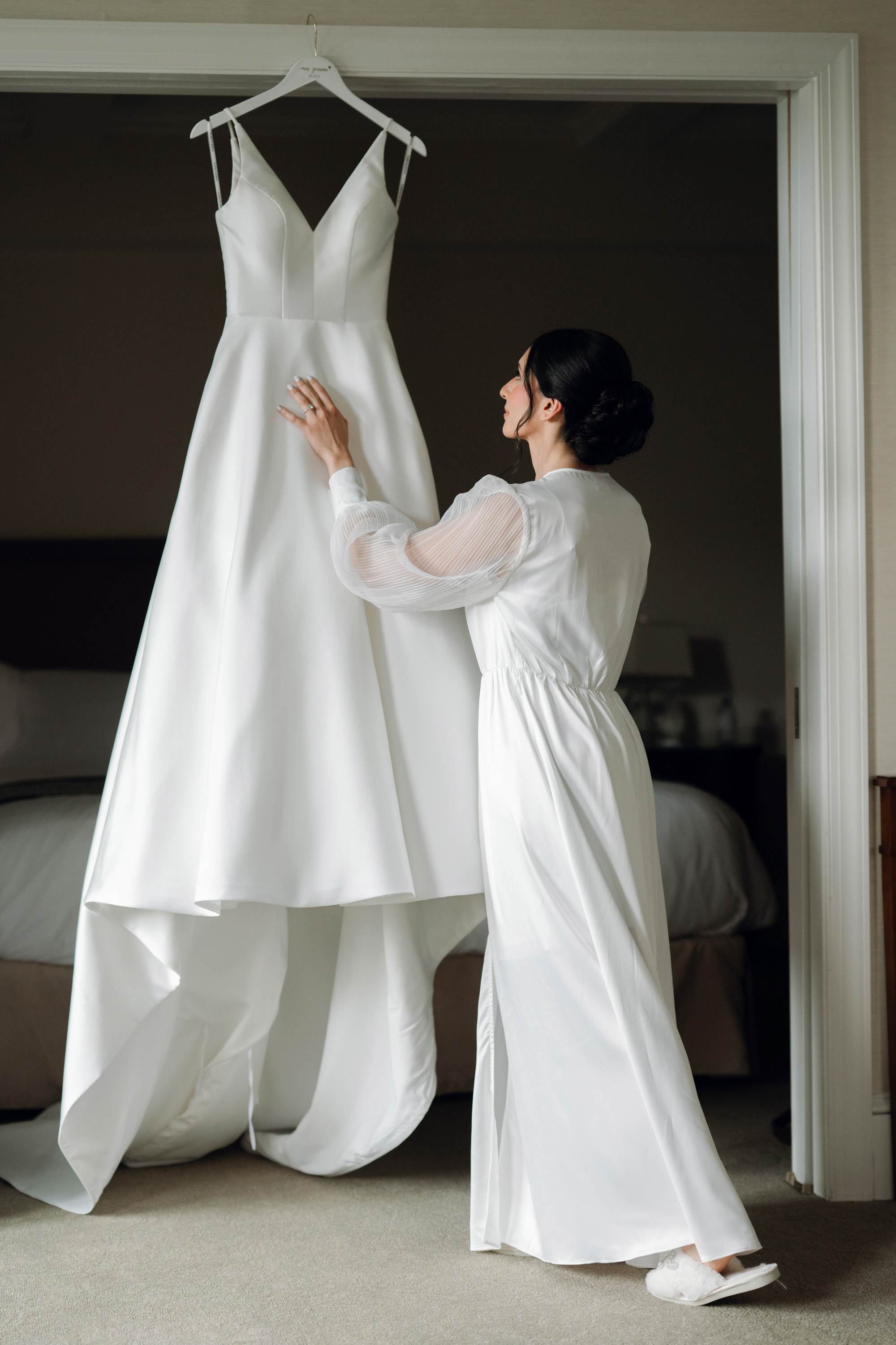 a woman in a white dress is trying to hang a wedding dress