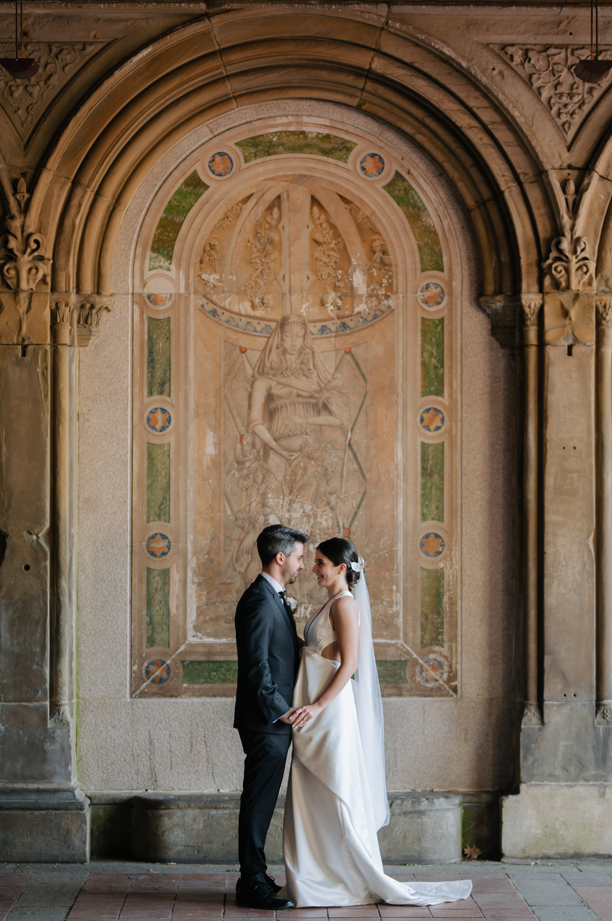 a bride and groom kissing in front of a wall